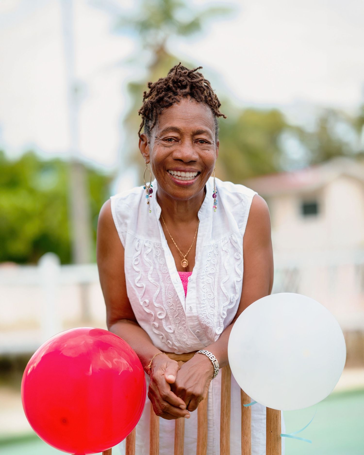 Outdoor portrait with red and white balloons wearing a white lace dress.