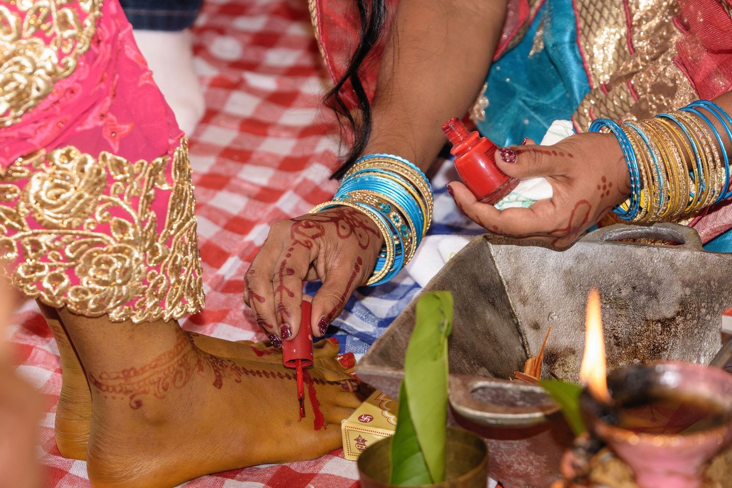 Close-up of traditional wedding ritual elements including henna decorated hands and ceremonial items.