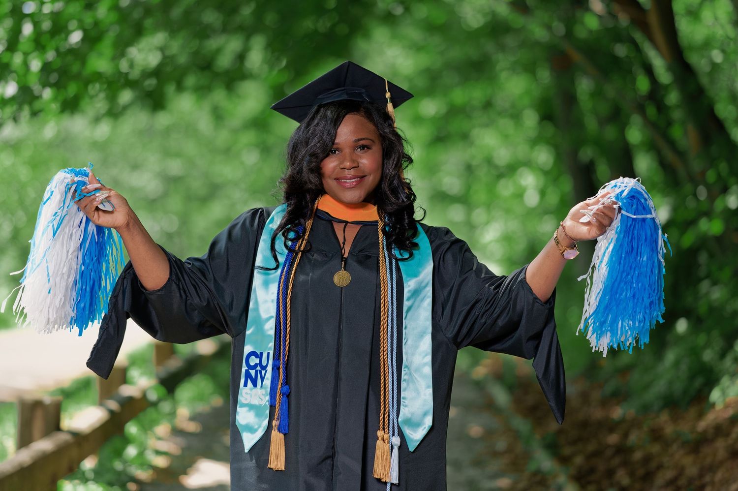 Graduates celebrating with blue and white tassels against green foliage.