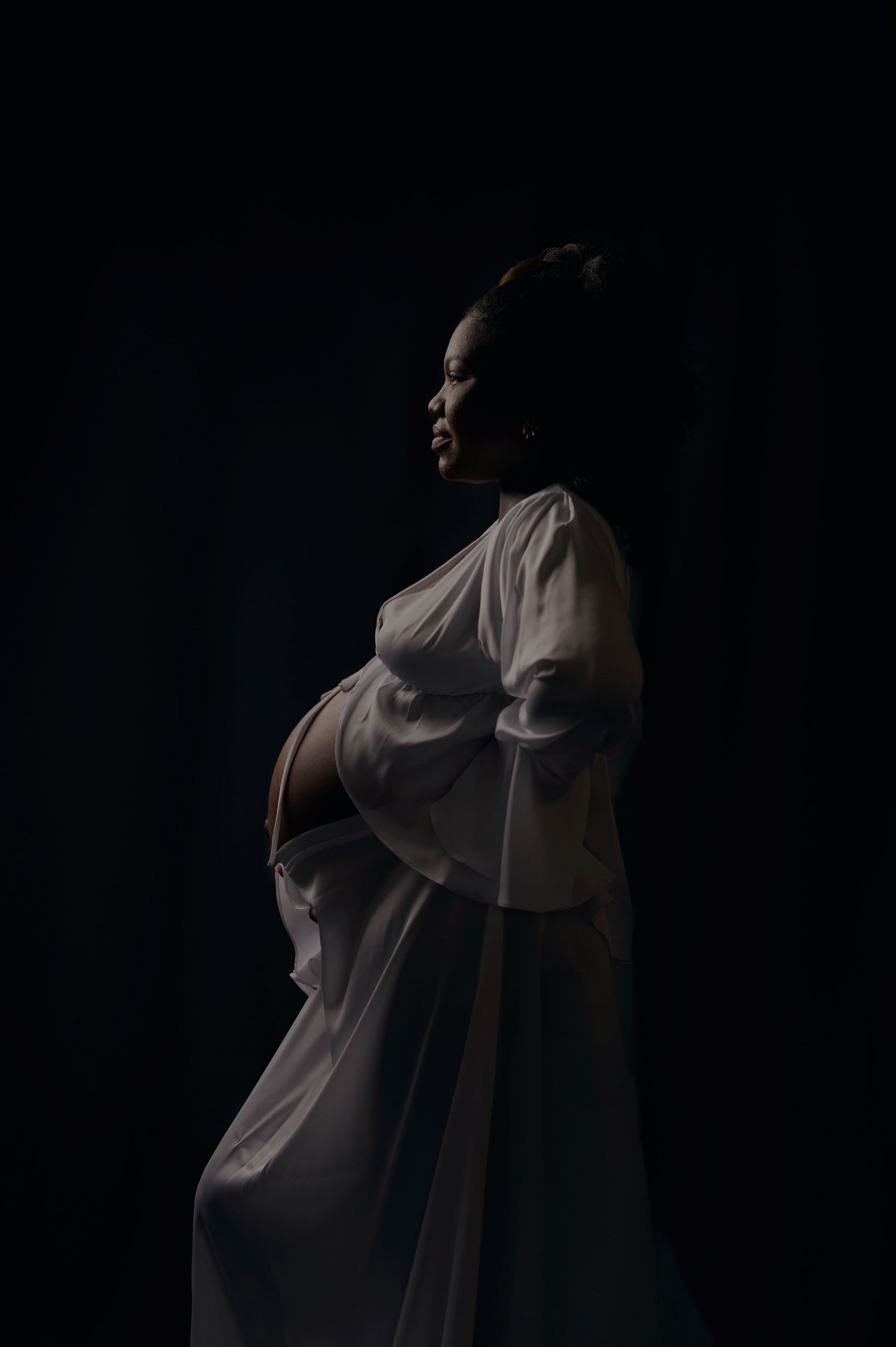 Dramatic silhouette of a figure in flowing white fabric against a dark background creating an ethereal artistic effect.