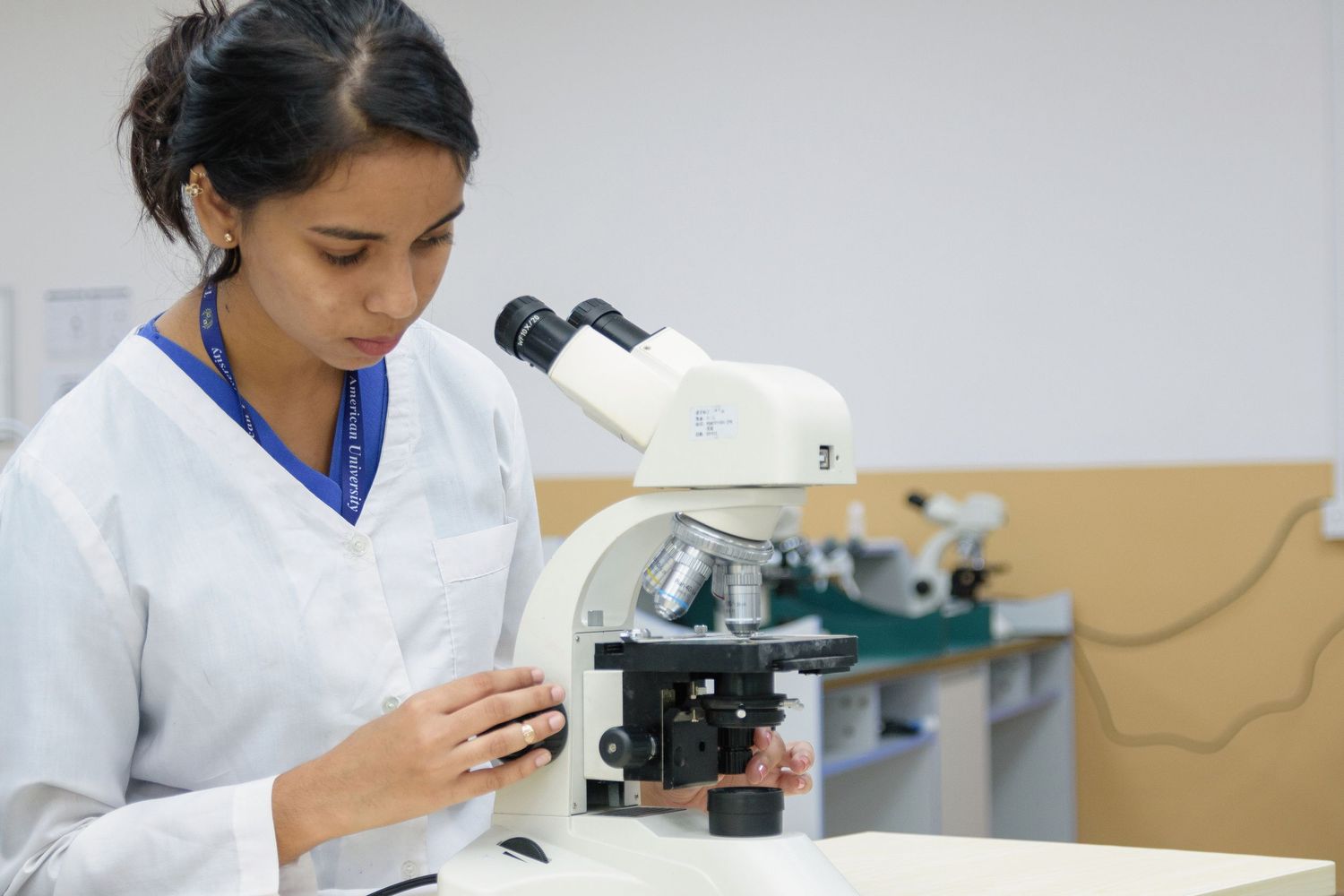 Scientists using microscopes and laboratory equipment for medical research and analysis.