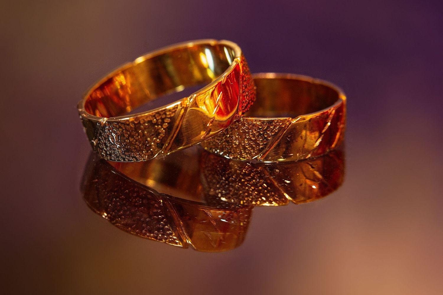 Close-up of golden wedding bangles with intricate designs in warm lighting.