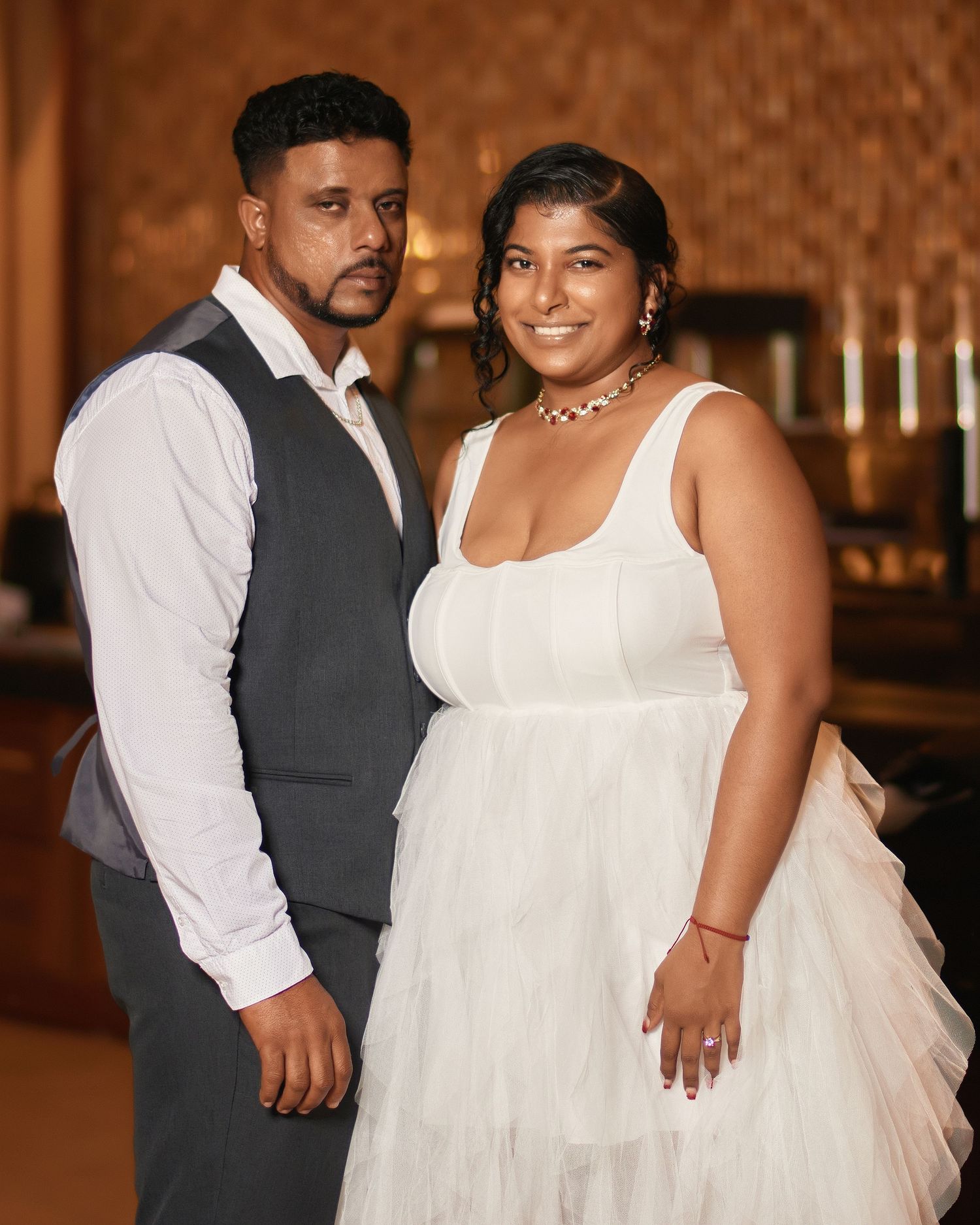 A romantic wedding photoshoot featuring a couple in formal attire dancing together in an elegant indoor setting.