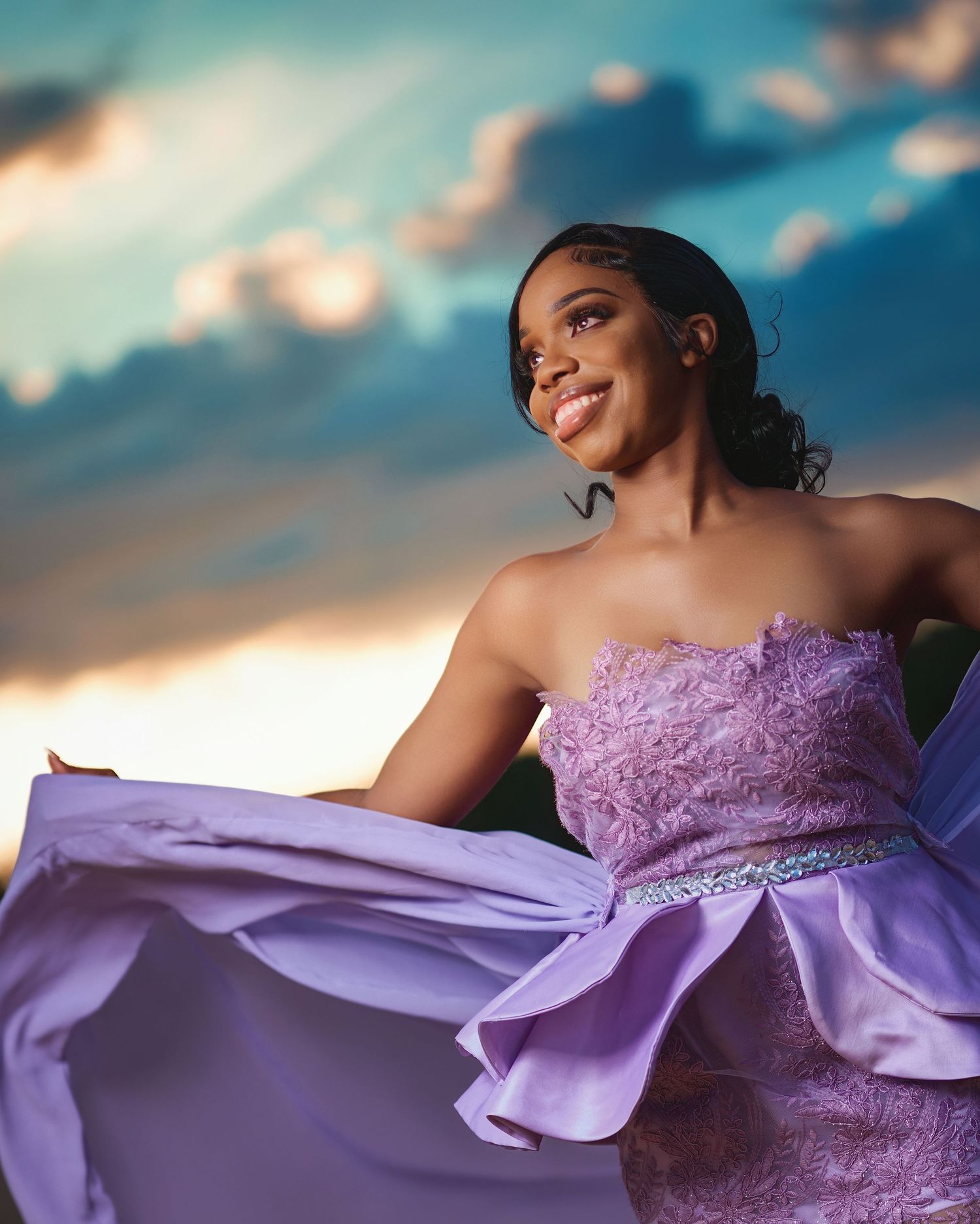 Dramatic sunset portrait in lavender formal dress with flowing fabric.