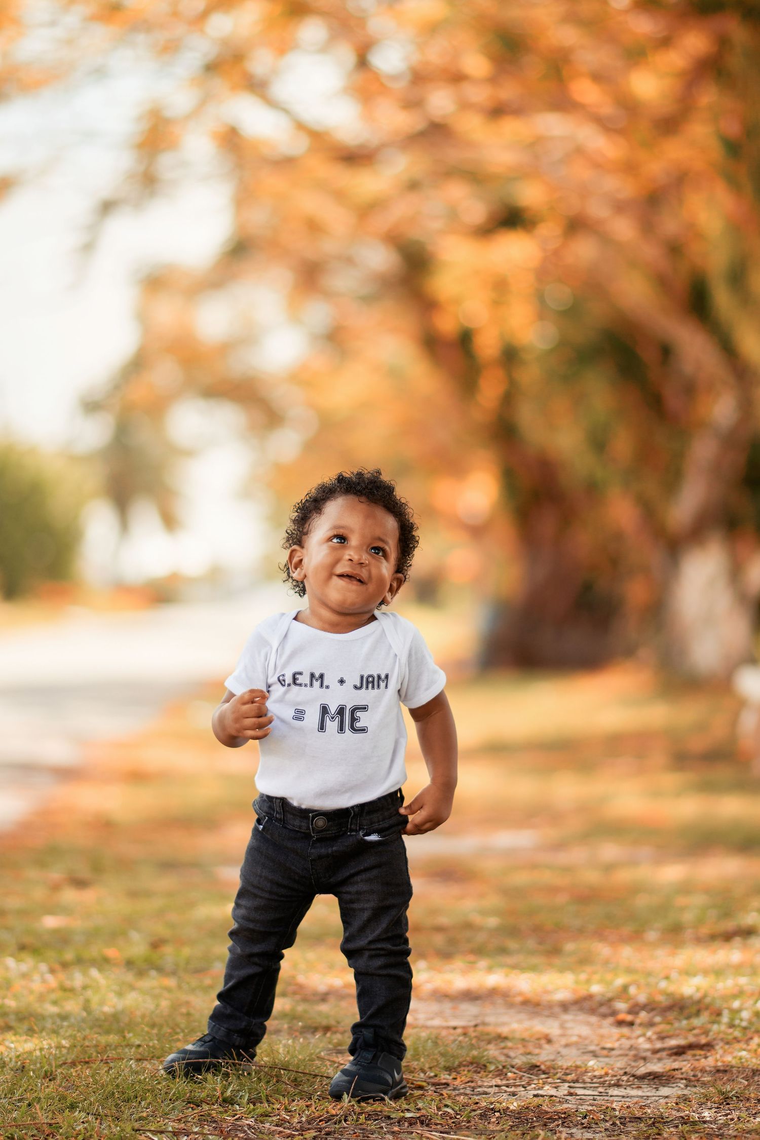 Small child taking first steps on autumn path with fallen leaves.