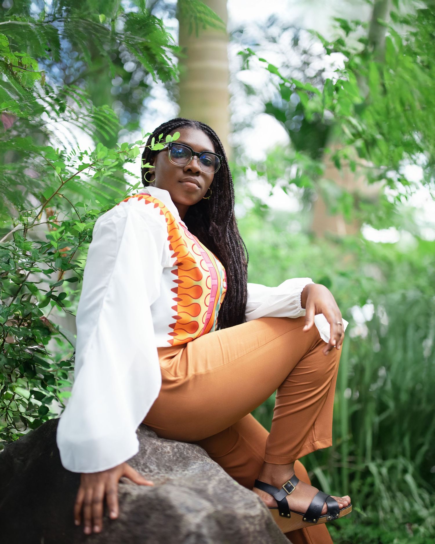 Casual outdoor portrait session with natural greenery and stone seating.