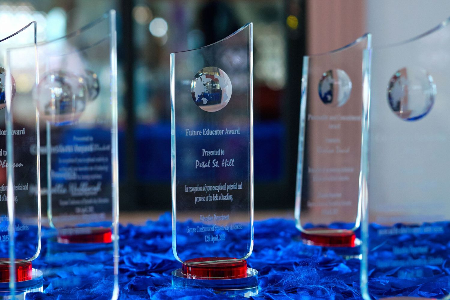 Close-up of transparent acrylic awards with blue bases lined up for display.