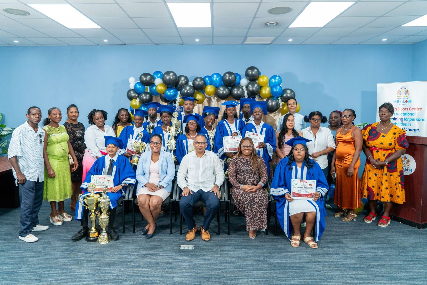 Large group panorama of graduation ceremony attendees in blue and white.