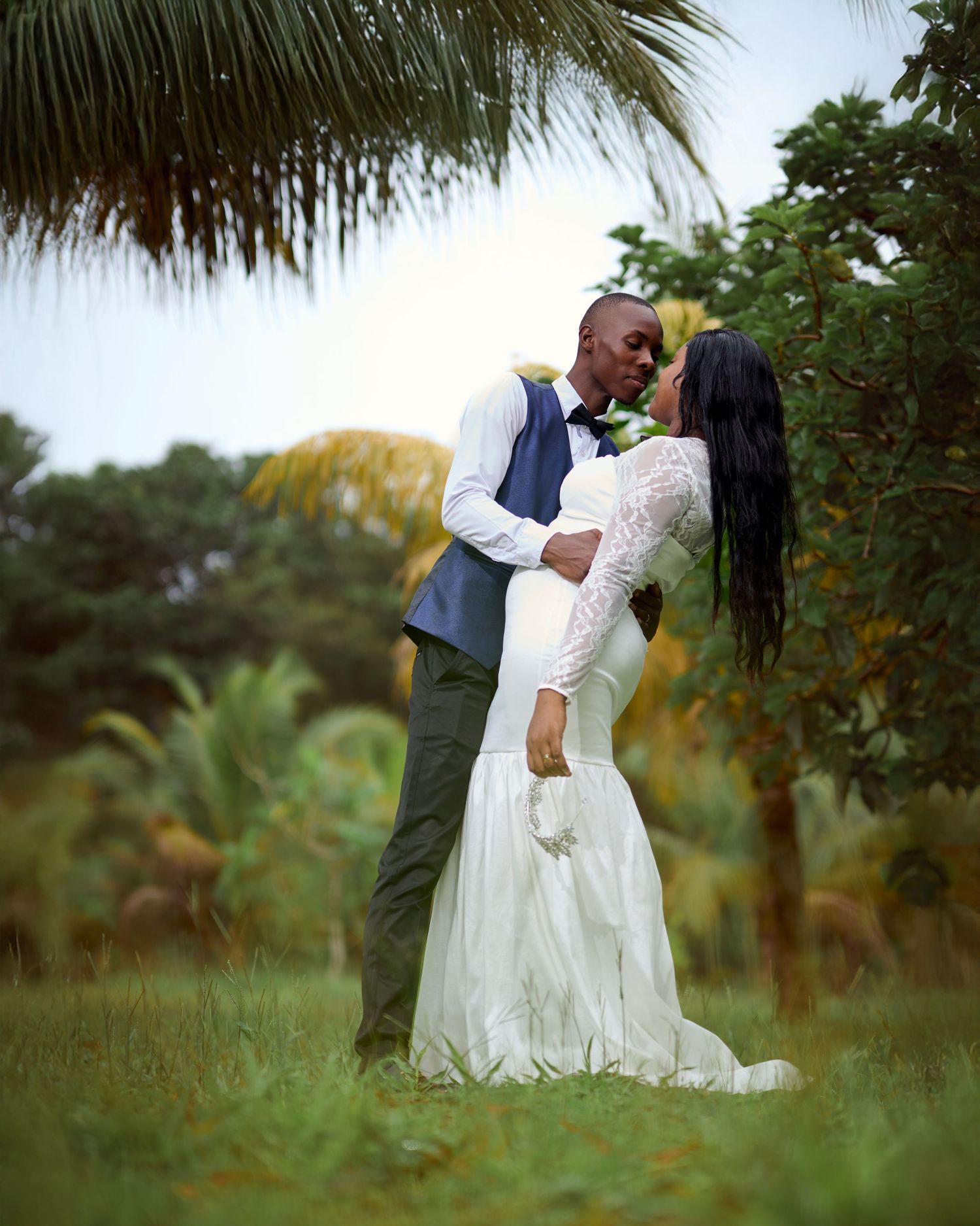A romantic wedding couple shares intimate moments in a lush tropical garden setting.