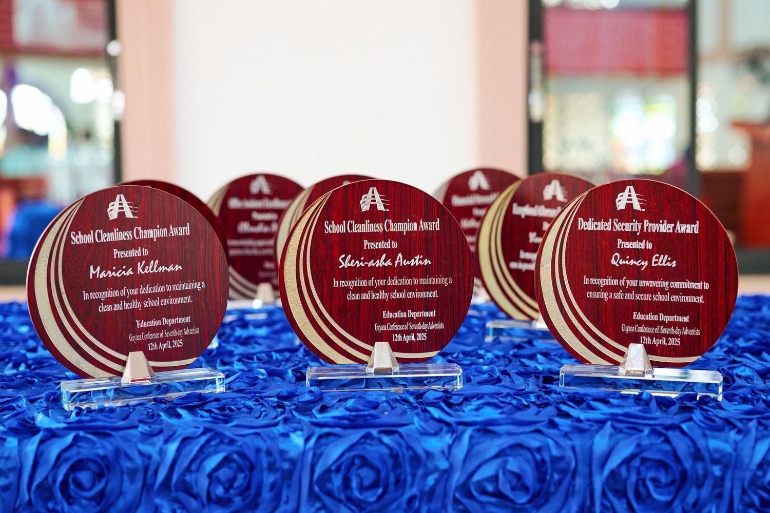 Row of red and clear acrylic awards displayed on blue fabric.