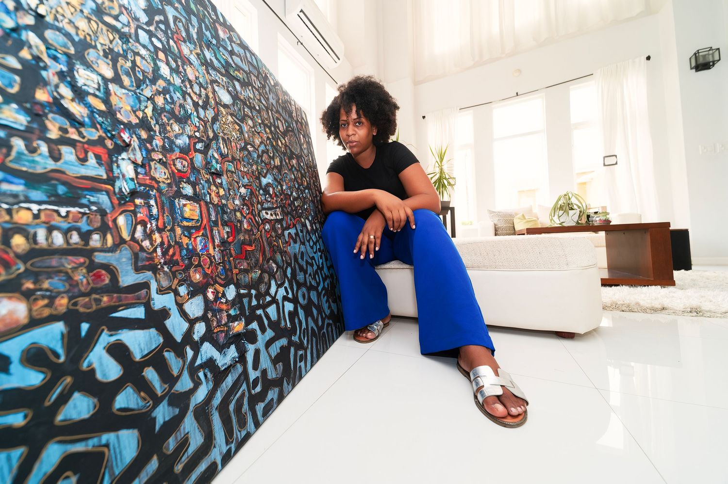 Artistic composition against a blue patterned wall in casual attire.