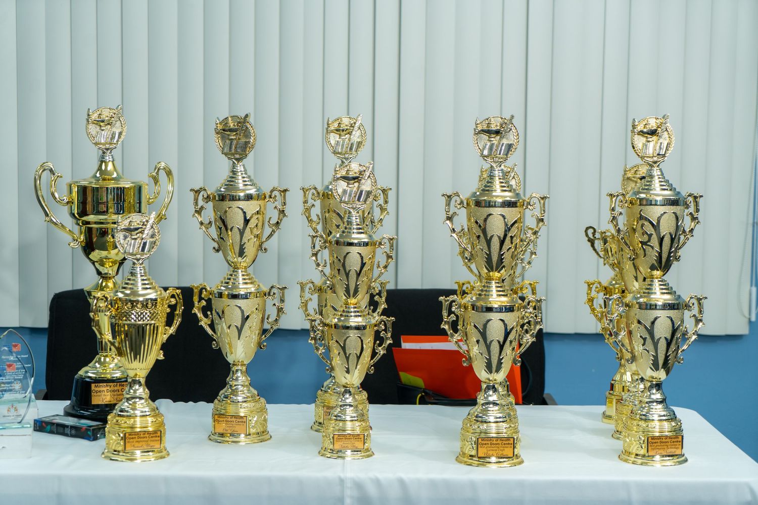 Display of golden trophy awards lined up on white surface.