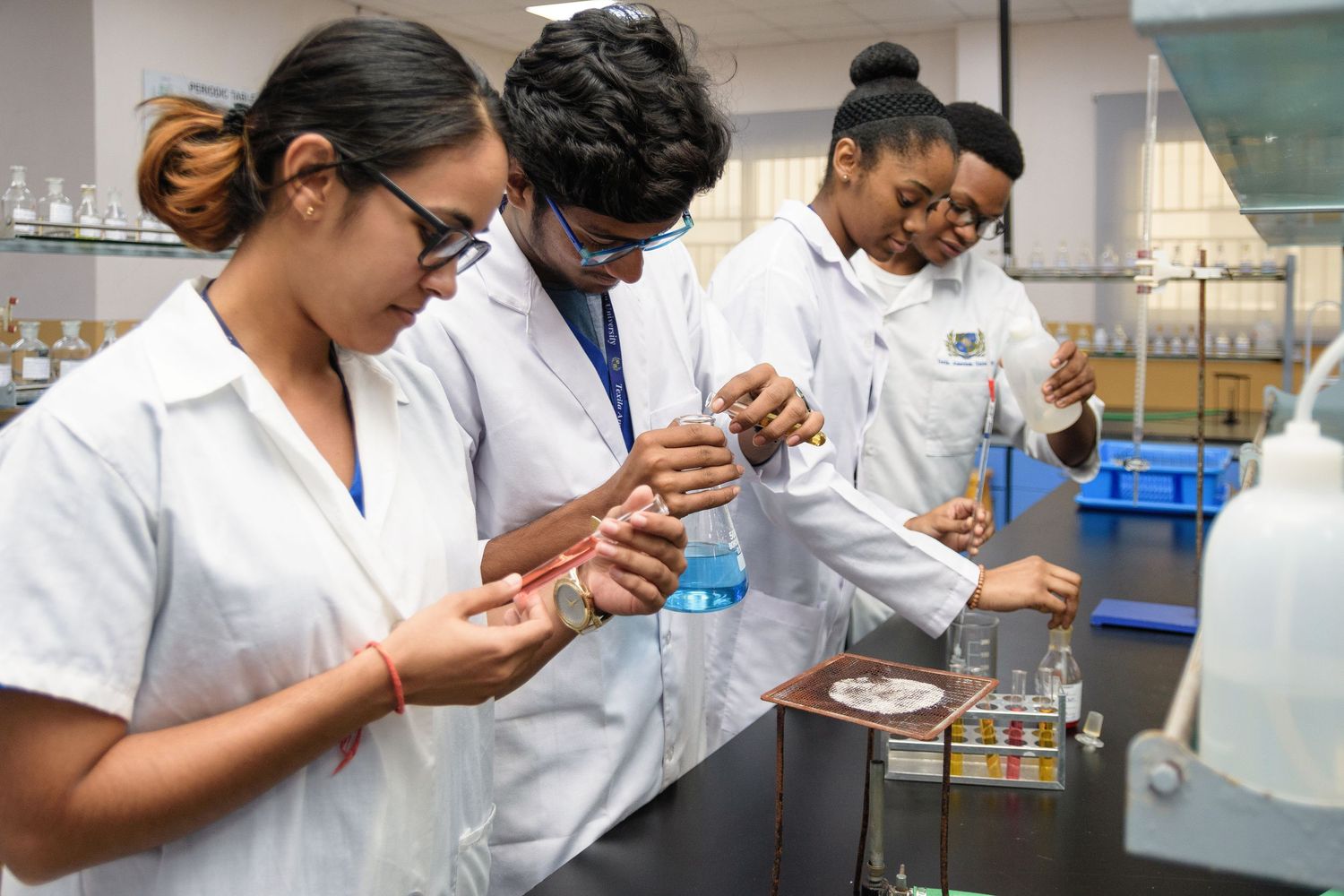 Students conducting experiments in a science laboratory while wearing protective gear.