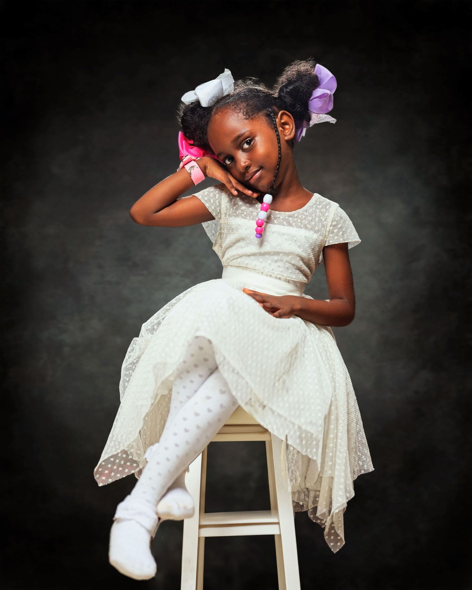 Studio portrait session featuring elegant white lace dress poses on a wooden stool.