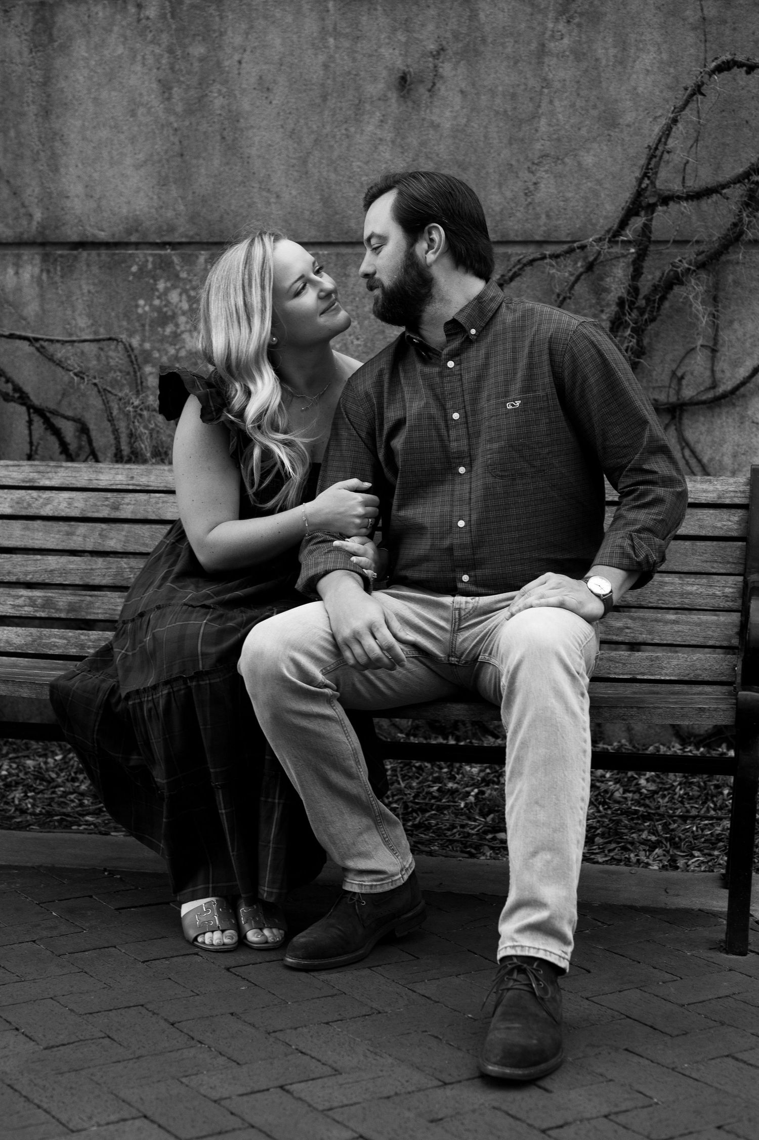 Black and white photo of a couple sharing a romantic moment on a park bench.