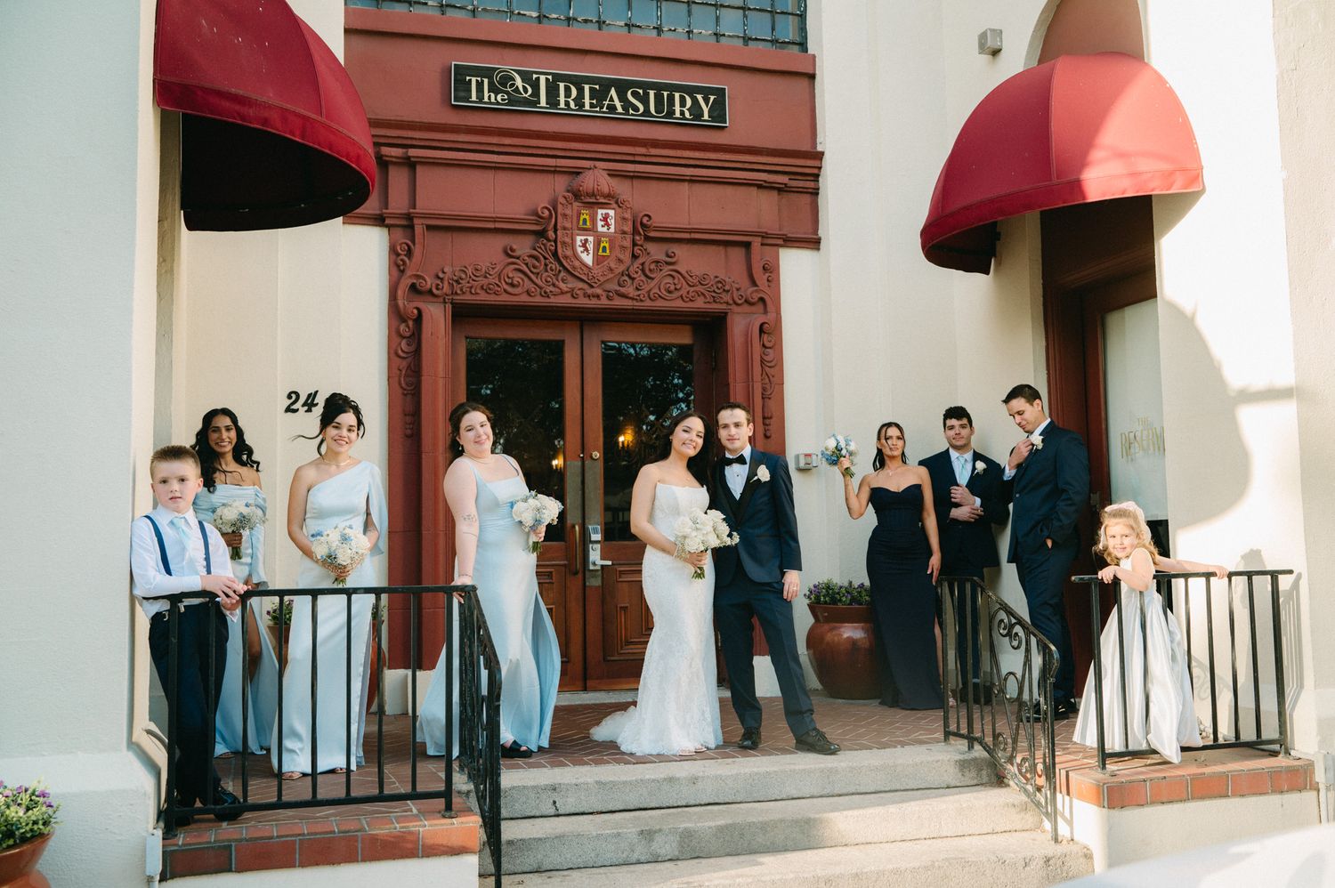 Wedding party posing outside The Treasury venue, bride and groom with bridesmaids and groomsmen on steps.