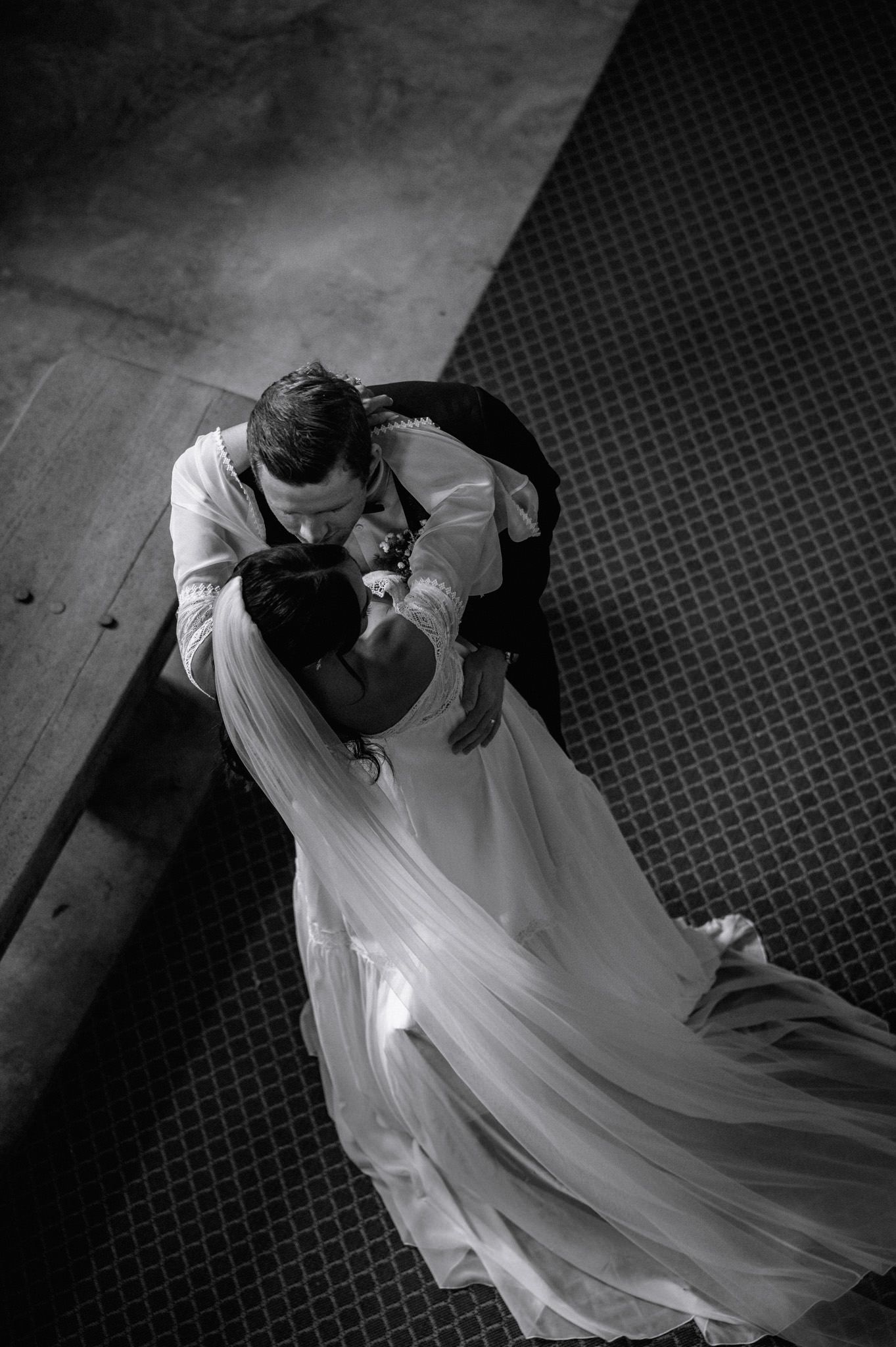 Aerial black and white shot of bride and groom sharing first dance, wedding gown flowing gracefully.