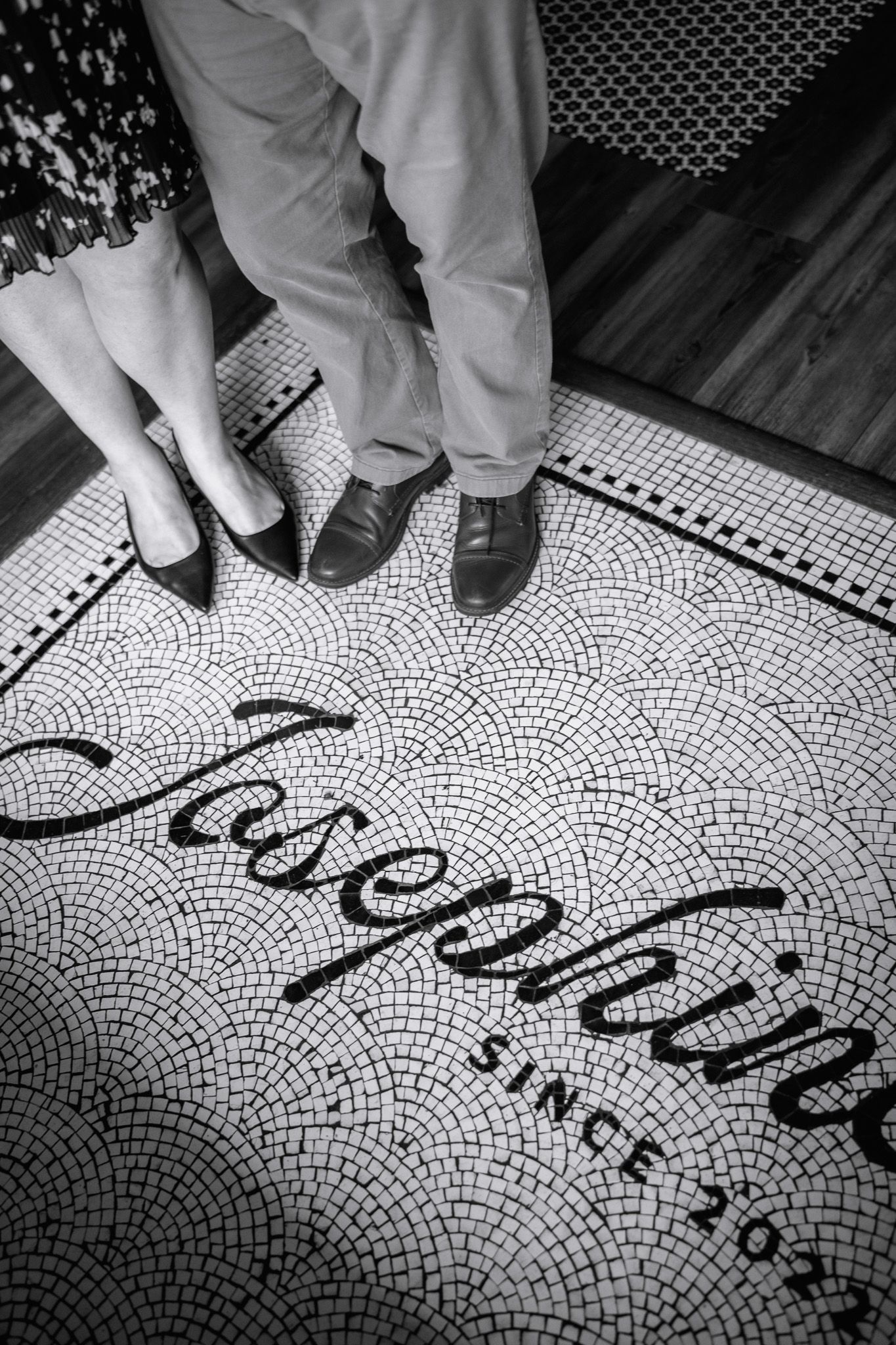 Black and white photo of two people standing on a mosaic tile floor reading Josephine Since 2022.