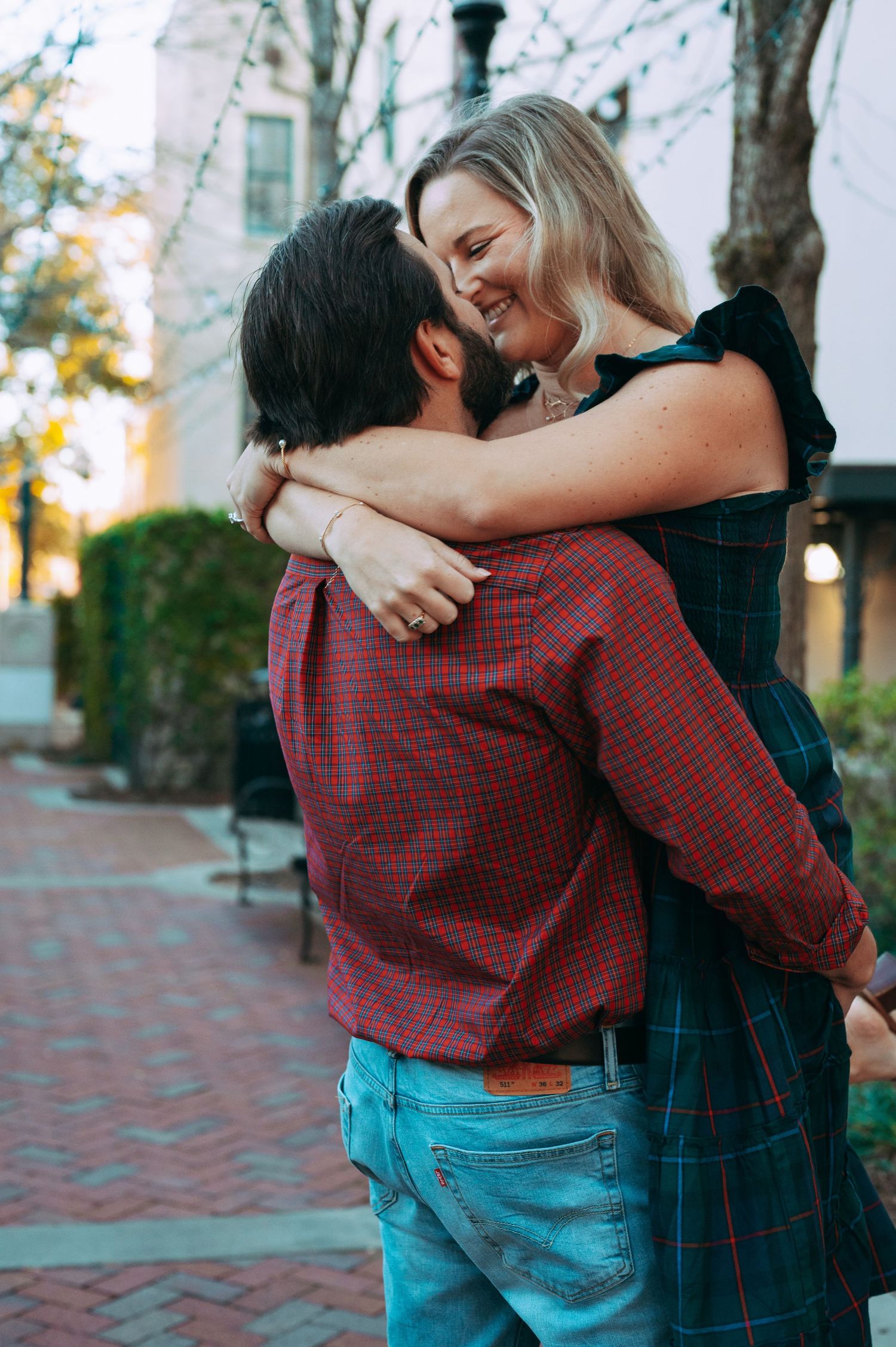 Happy couple embracing and laughing together on a charming brick sidewalk outdoors.
