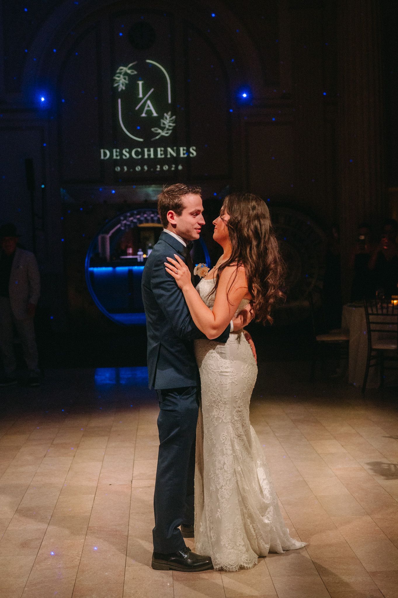 Newlyweds share their first dance under a monogram projection at the Deschenes wedding reception.