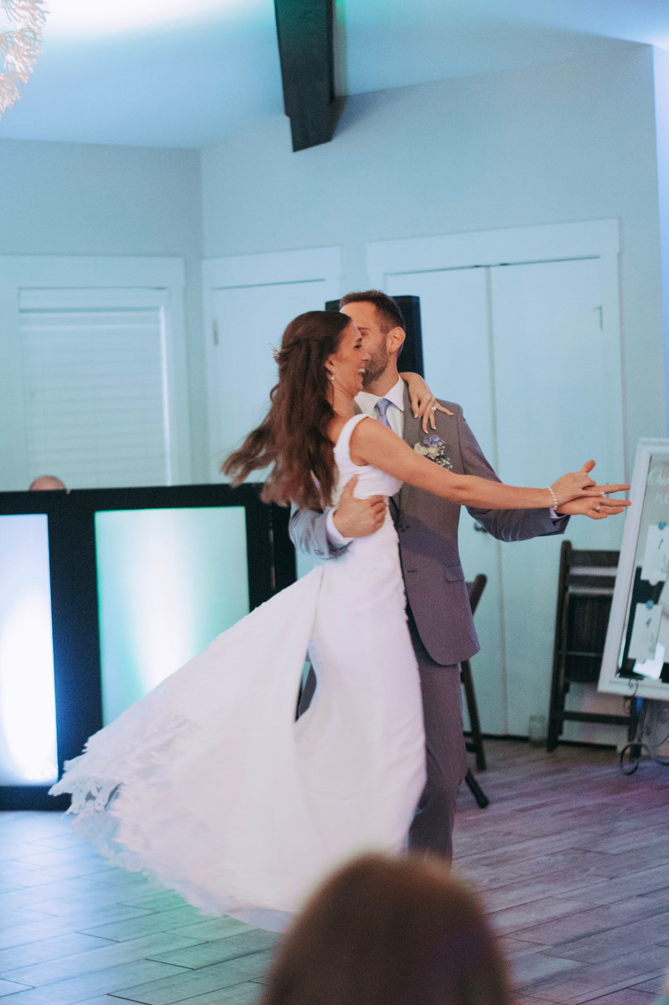 Groom lifting bride in a dramatic spin during energetic first dance at wedding reception.