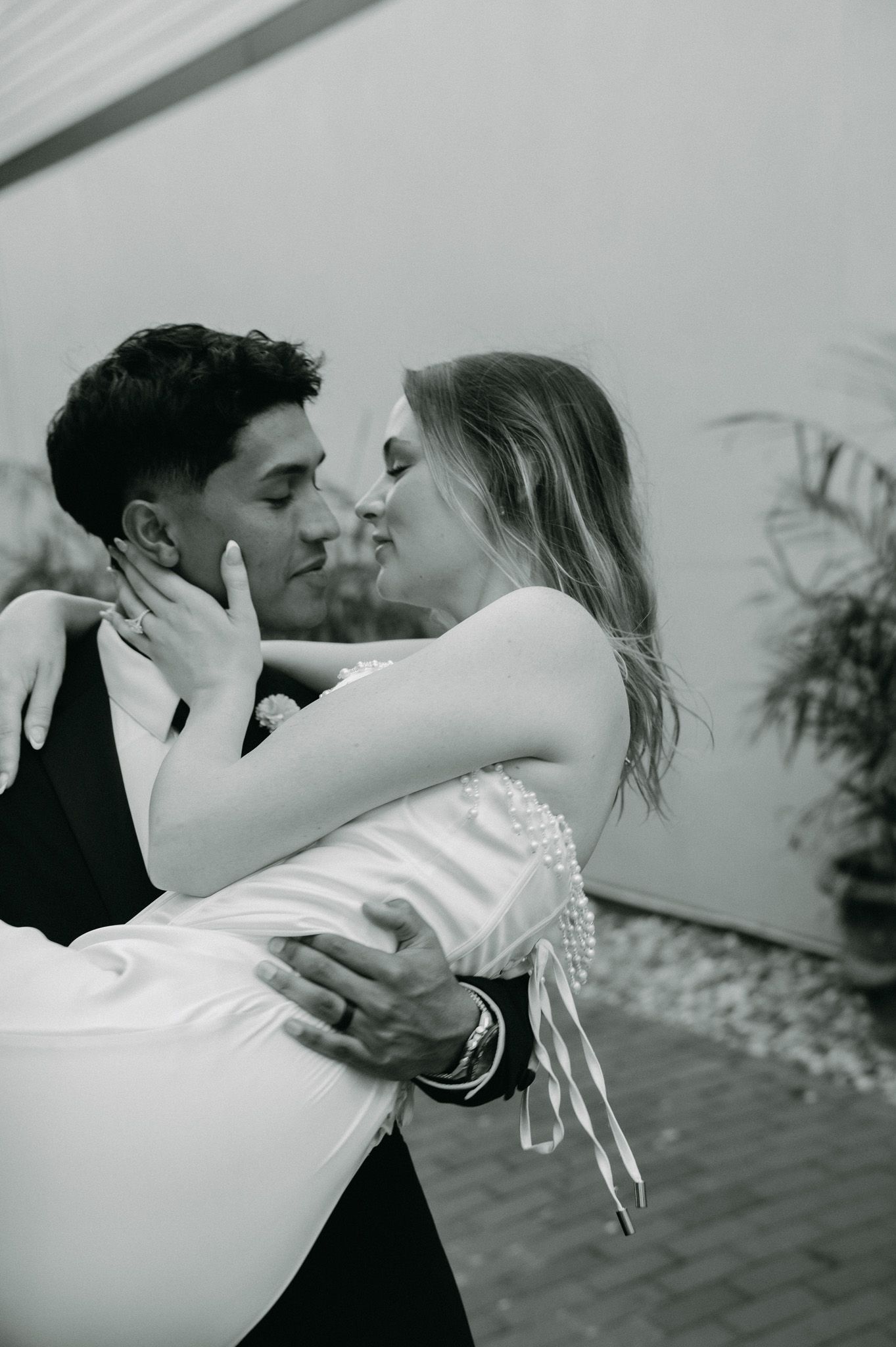 Groom lifting bride for romantic kiss in black and white wedding portrait outdoors.