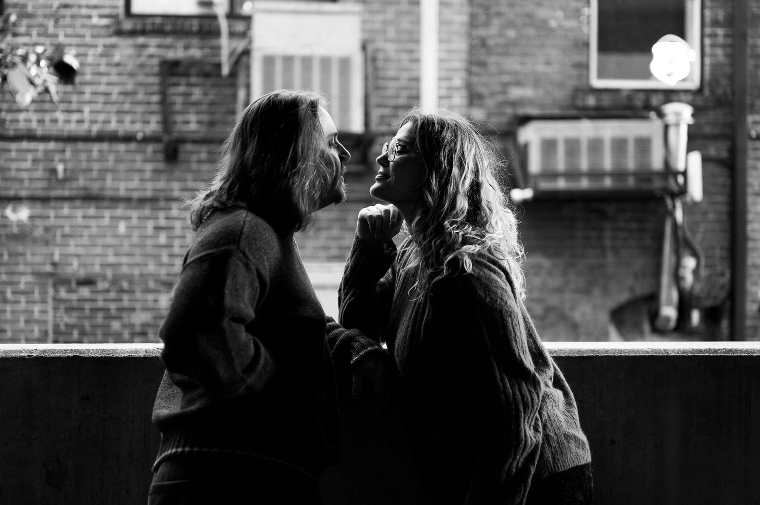 Black and white photo of two people facing each other intimately at night outdoors.