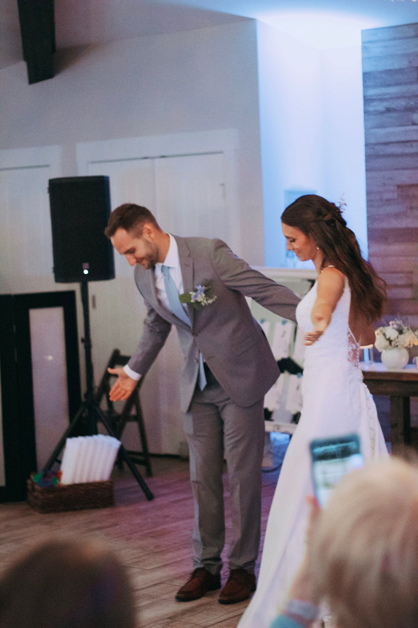 Bride and groom taking a playful bow together on the dance floor at wedding reception.