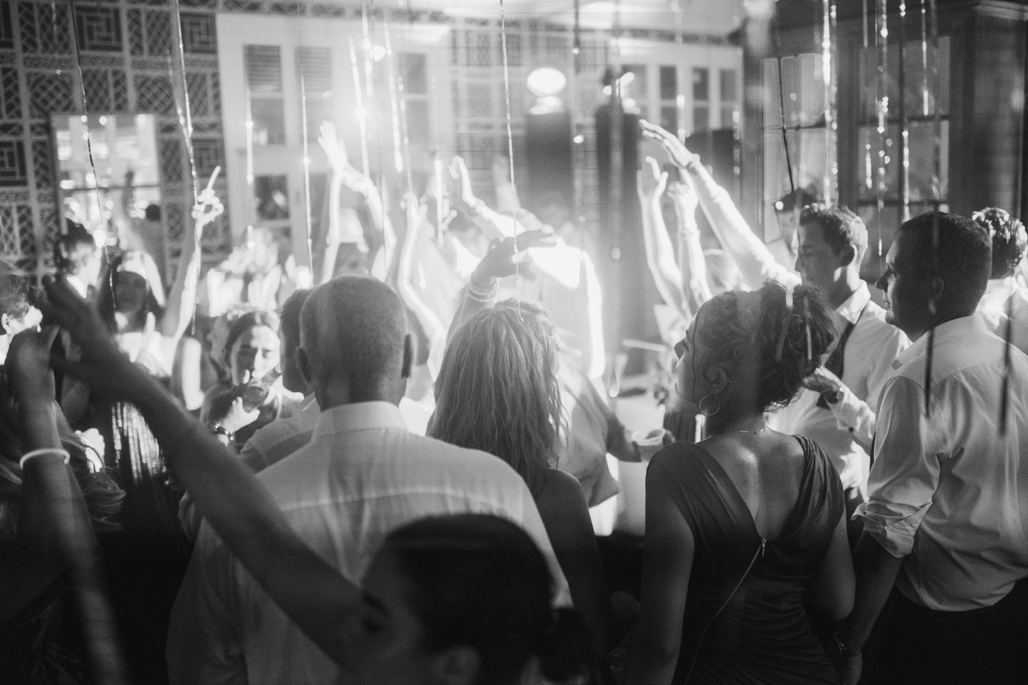 Black and white panoramic photo of a crowded nightclub dance floor with people dancing under atmospheric lighting.