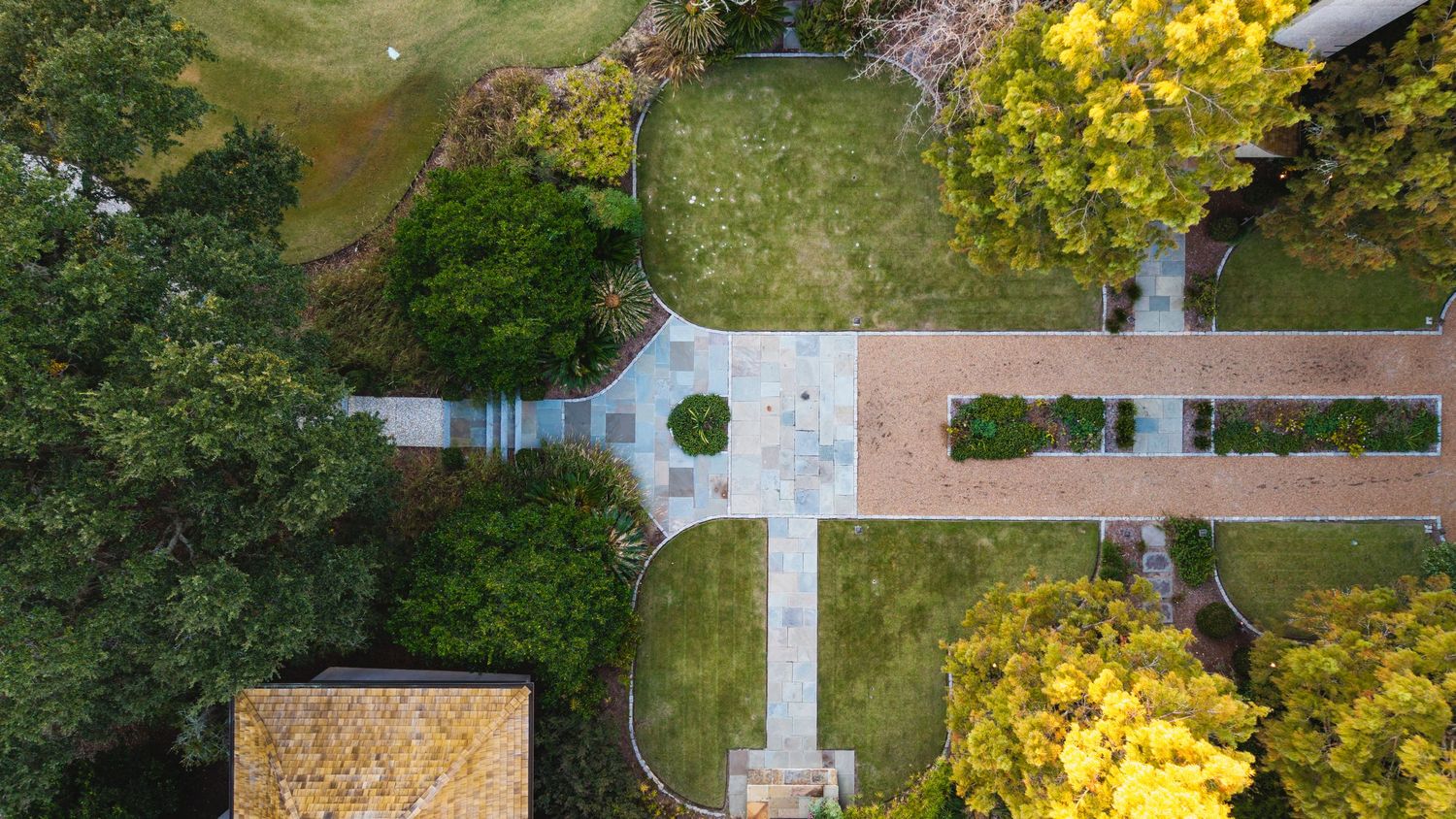 Aerial view of a lush green golf course with trees and winding paths during summer.