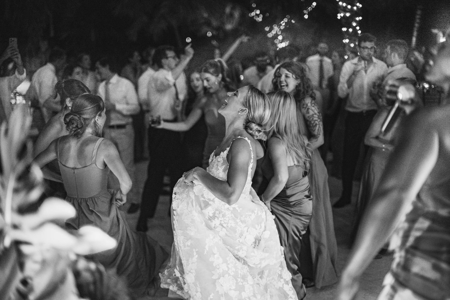 Wedding reception dance floor filled with guests celebrating under dim lighting.