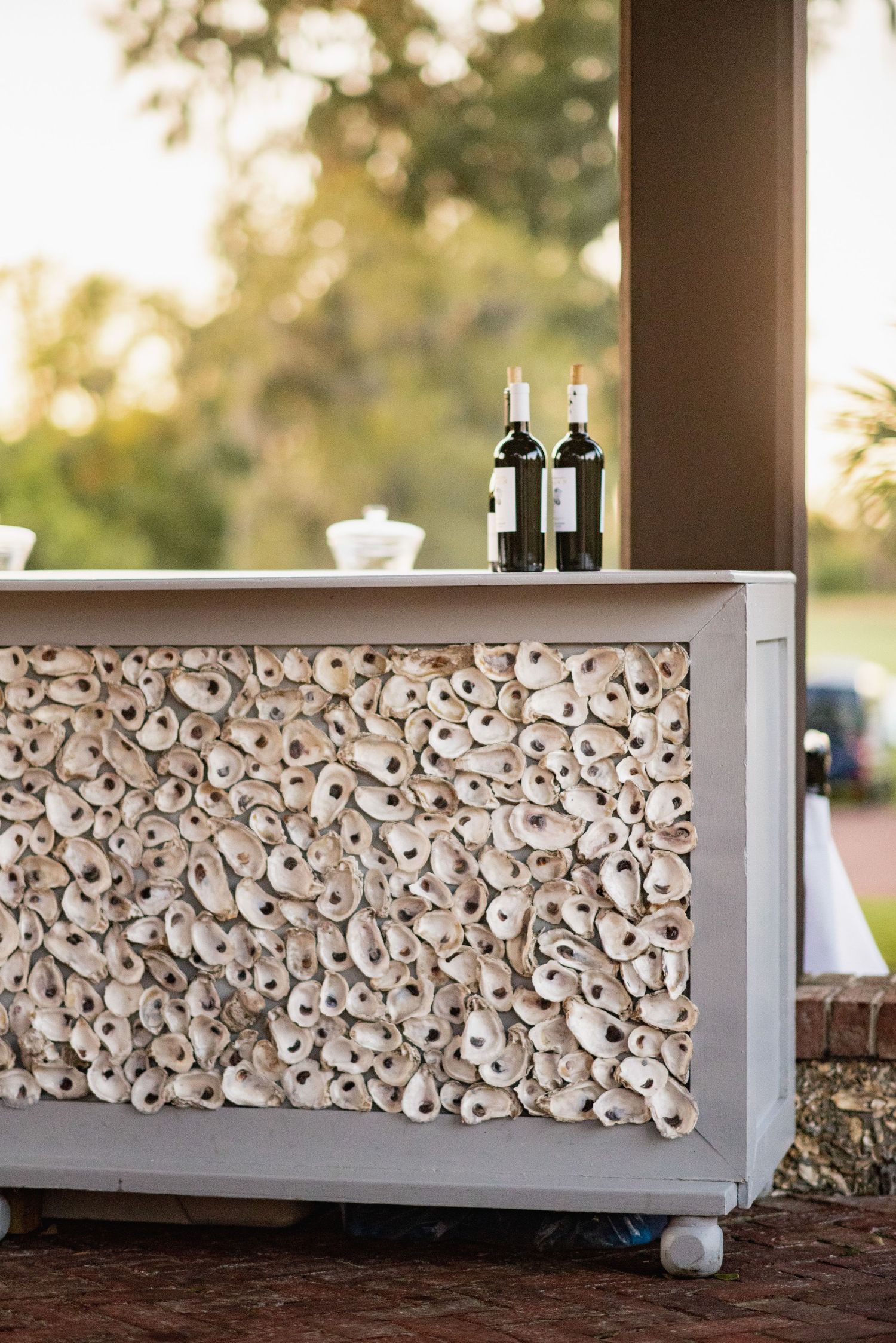 White oyster shells arranged in a decorative pattern on a modern bar counter at an outdoor venue.
