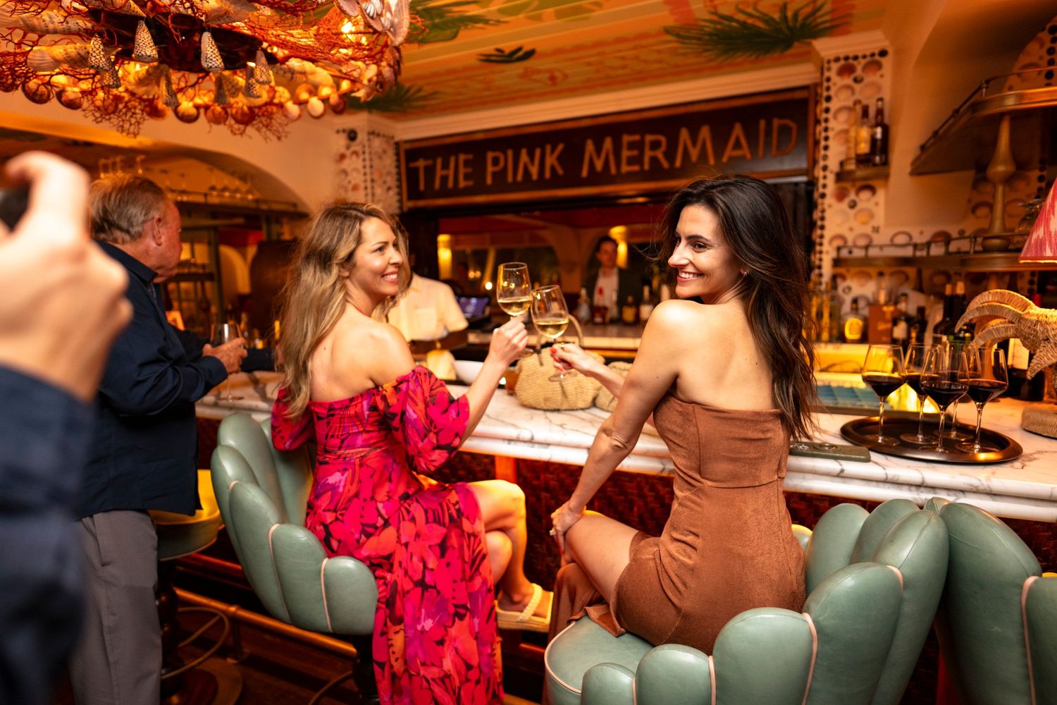 Cozy restaurant interior with warm lighting and rustic decor featuring a pink mermaid sign.