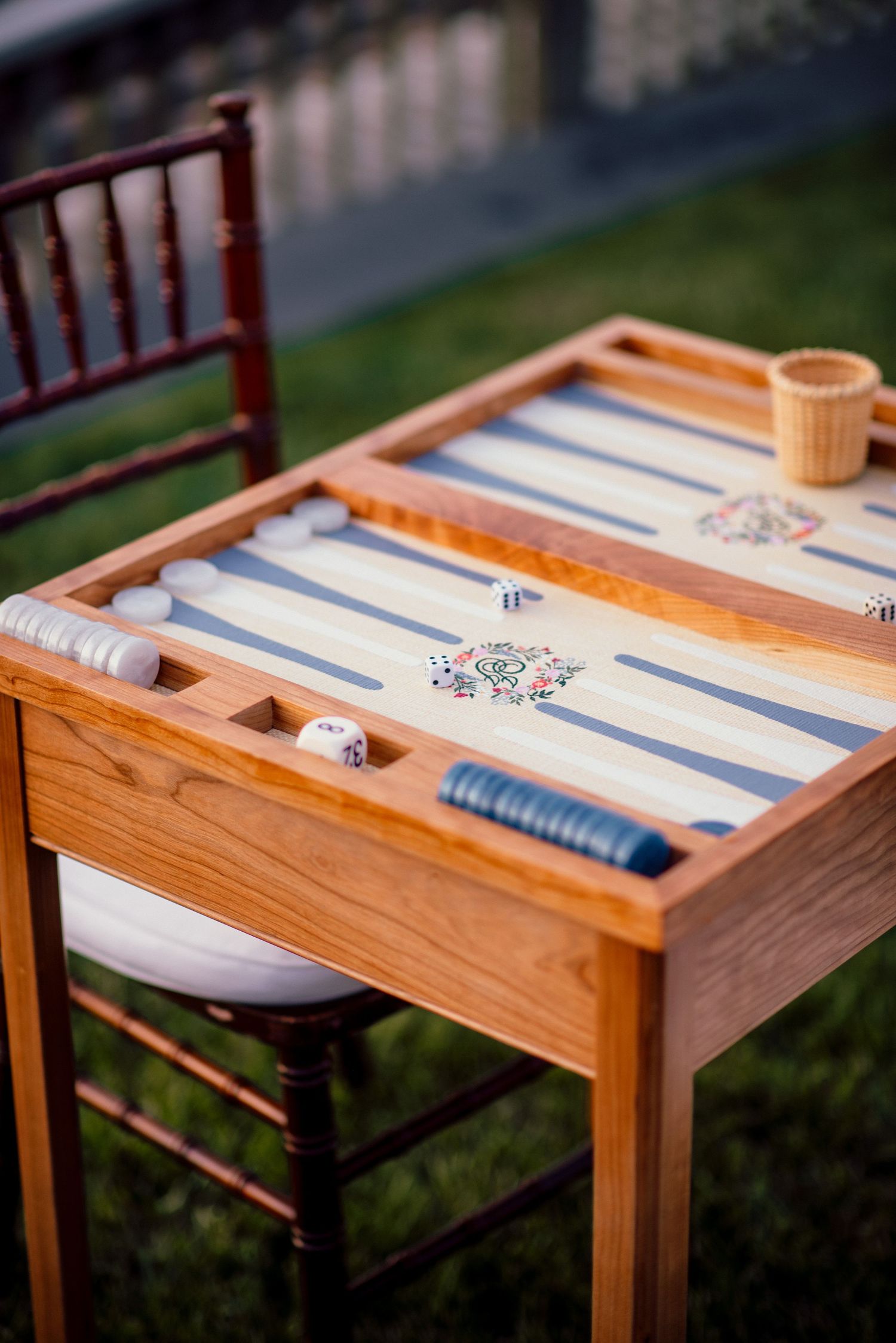 Wooden backgammon board game set up on outdoor table at wedding reception.