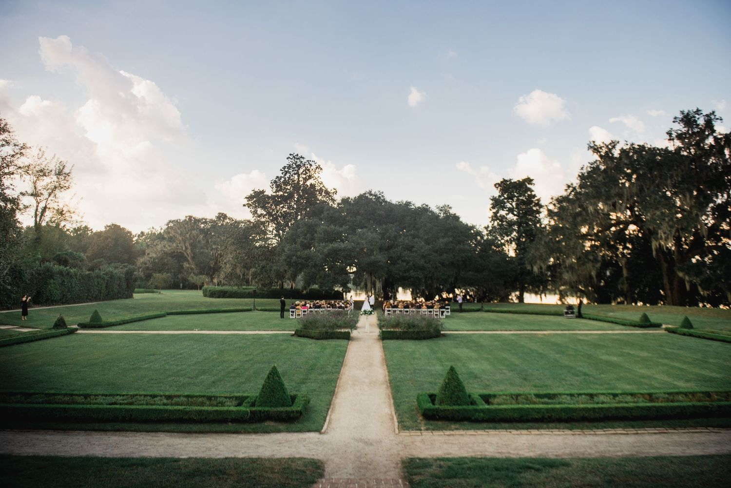 A panoramic view of a peaceful golf course at sunset with rolling green fairways and scattered trees in the distance.