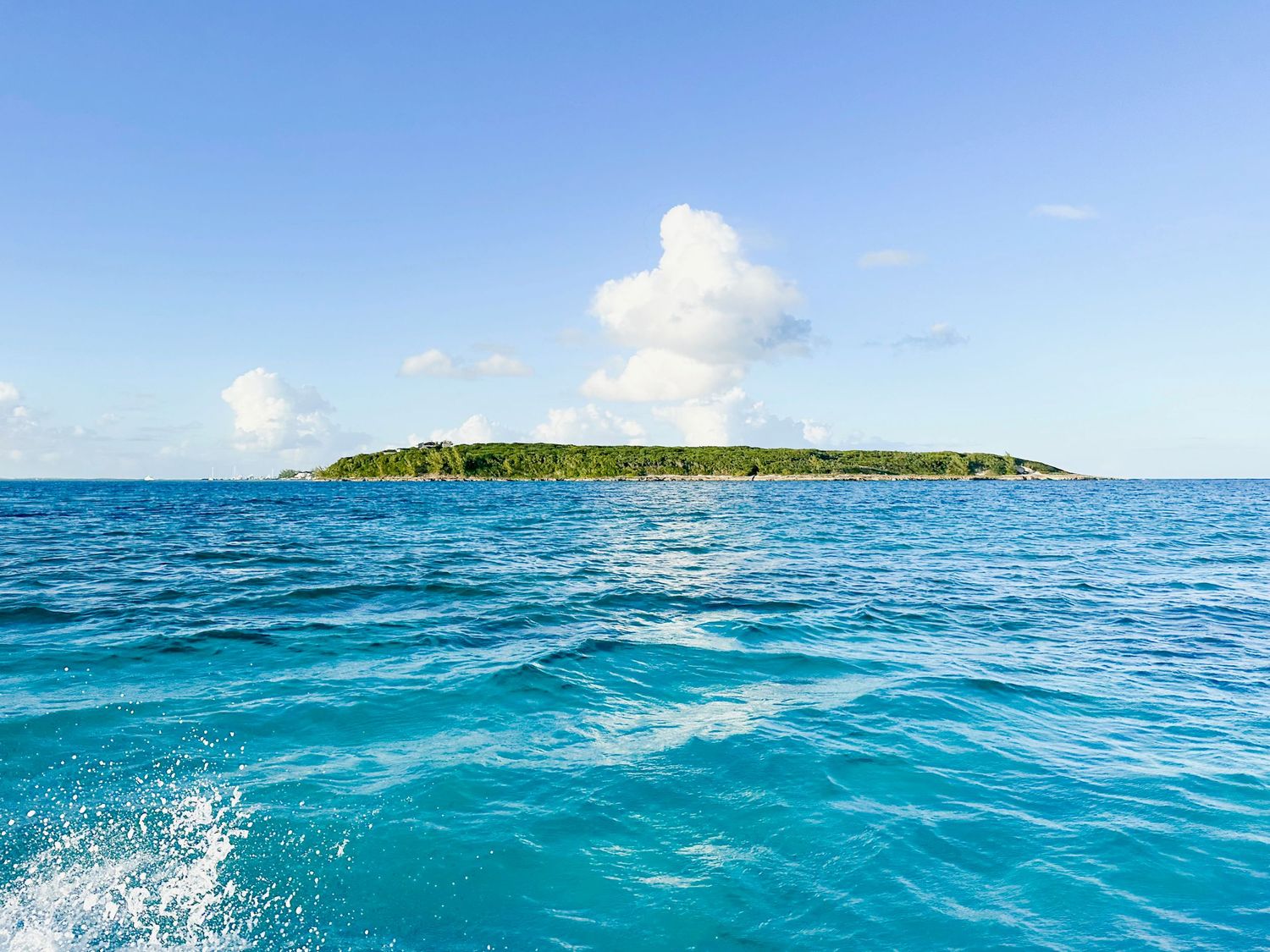 Panoramic view of crystal clear turquoise ocean waters stretching to the horizon under blue skies.