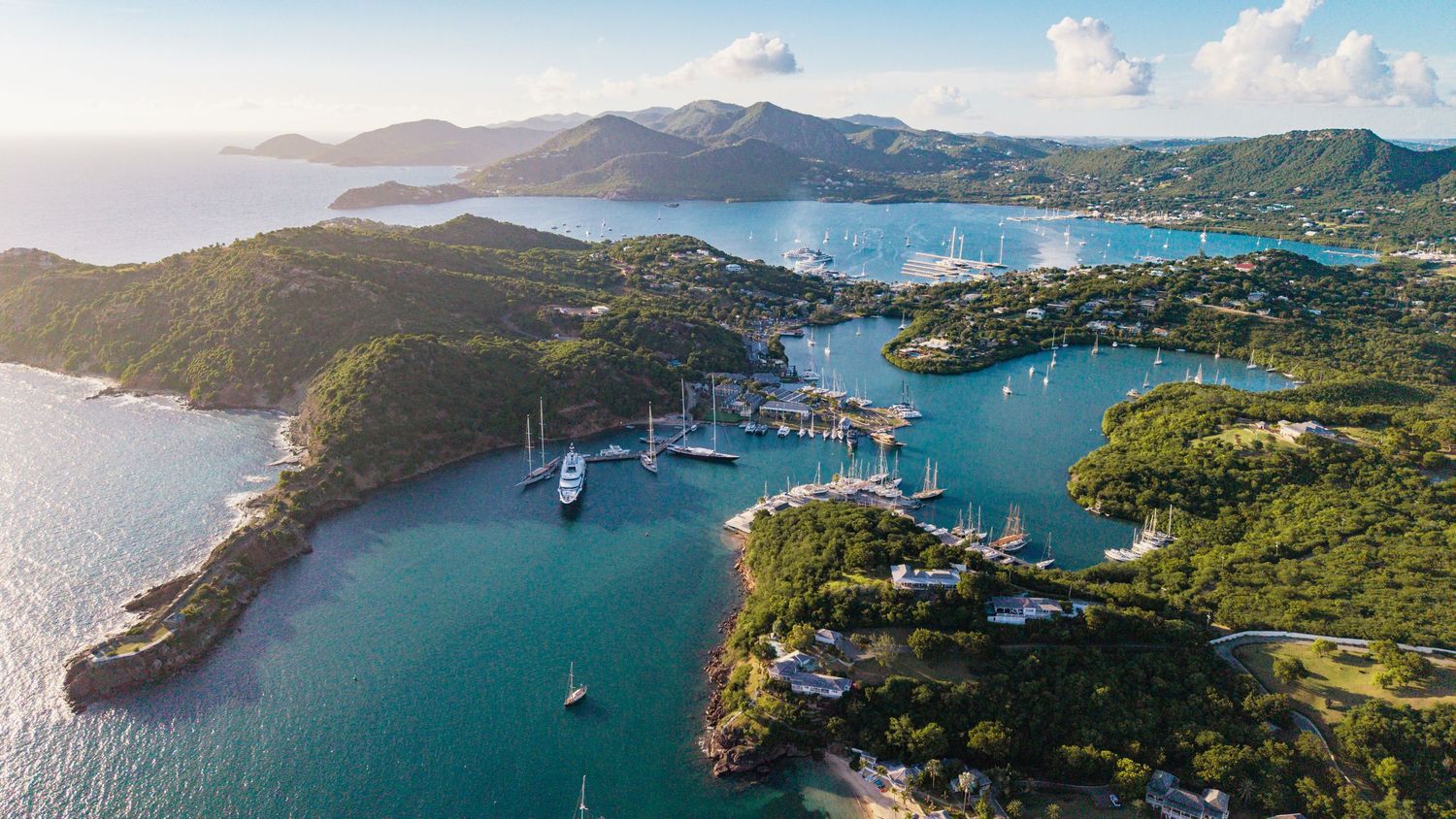Aerial panorama of a tropical bay in Antigua with boats anchored in crystal clear blue waters.