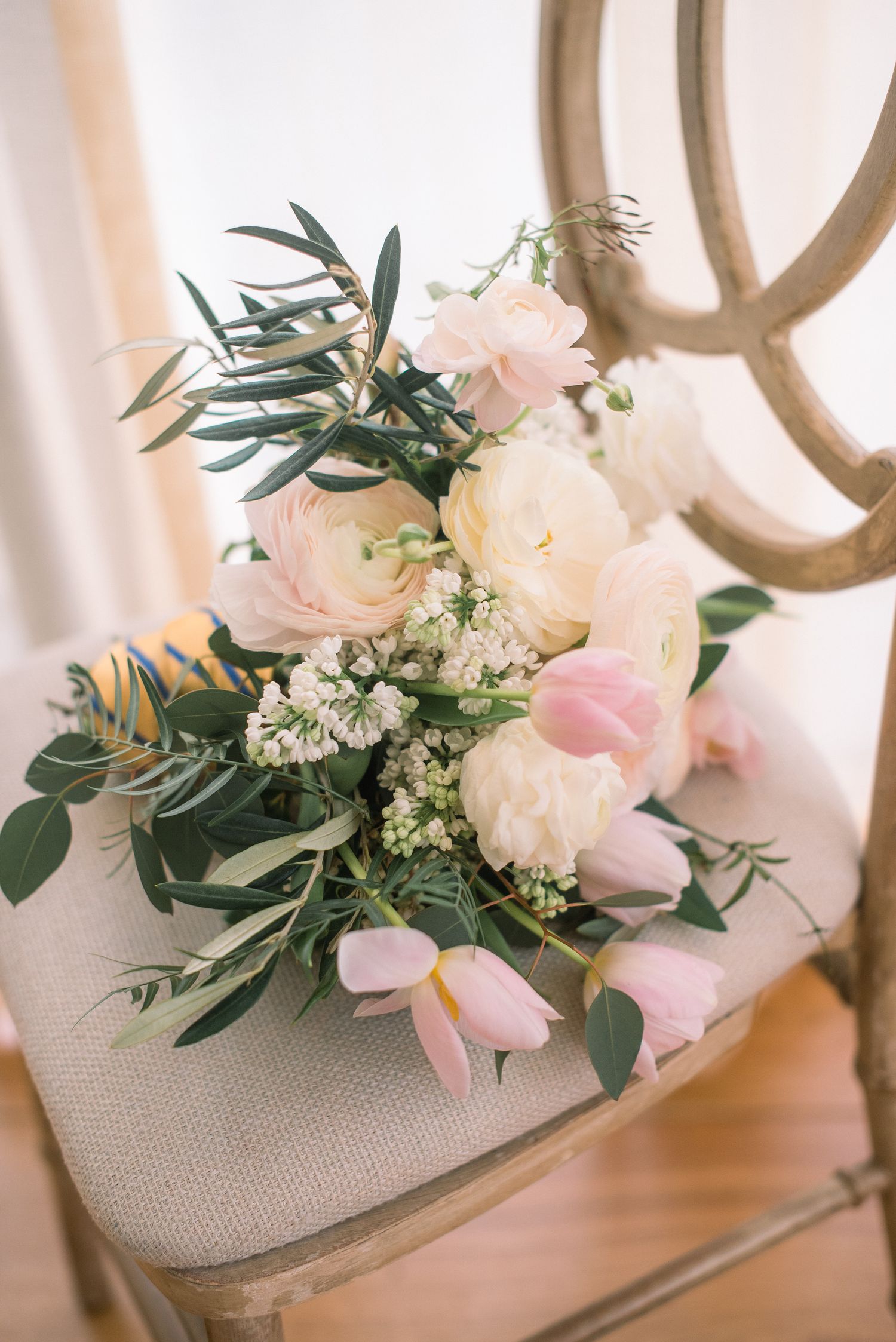 Elegant bridal shoes decorated with delicate pink and white floral arrangements and greenery for a wedding.