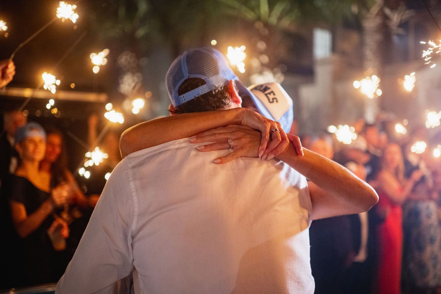 A couple dances at a wedding reception while guests hold sparklers creating a magical light tunnel effect.