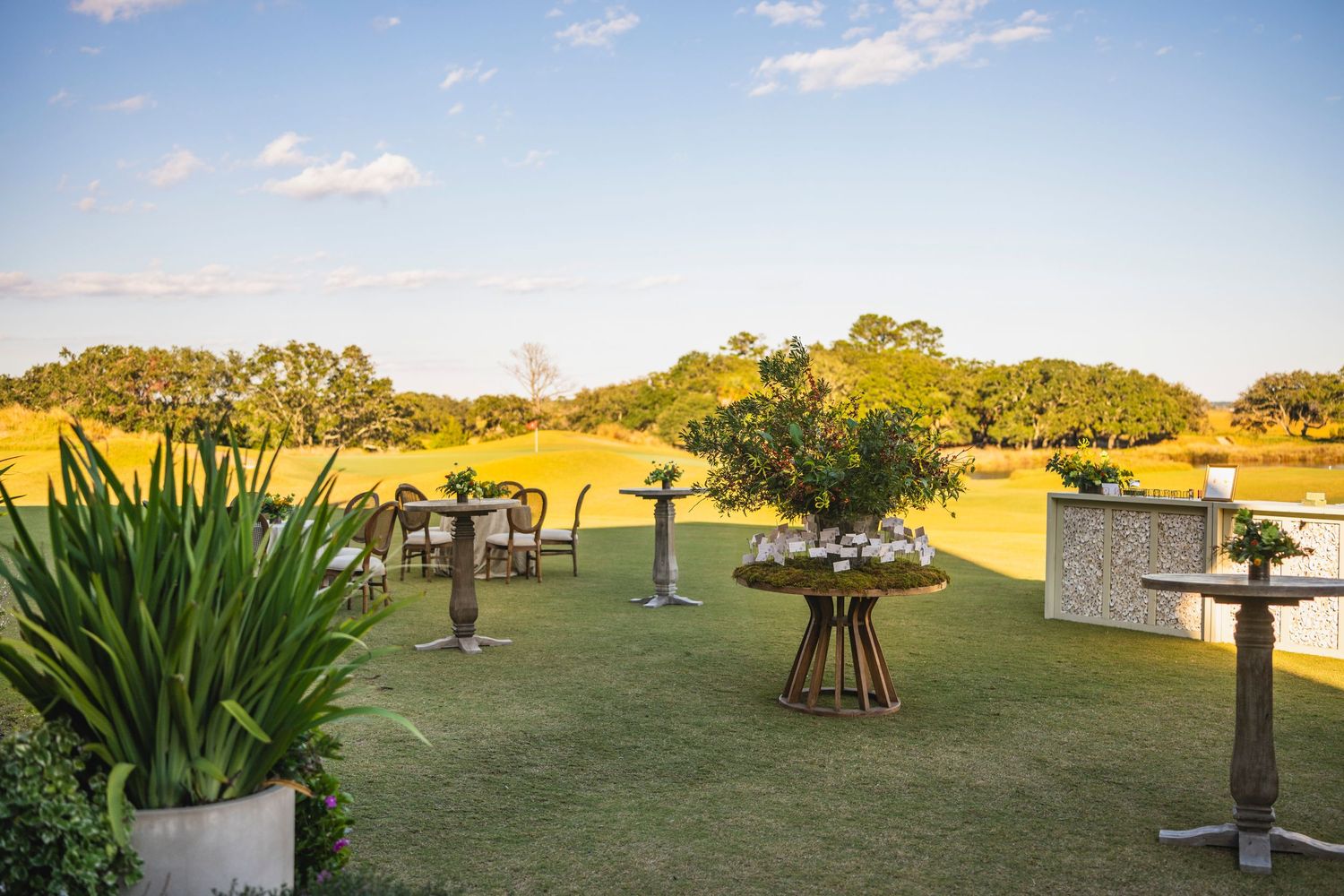 Panoramic view of a grassy field at sunset with scattered outdoor sculptures and installations in the distance.