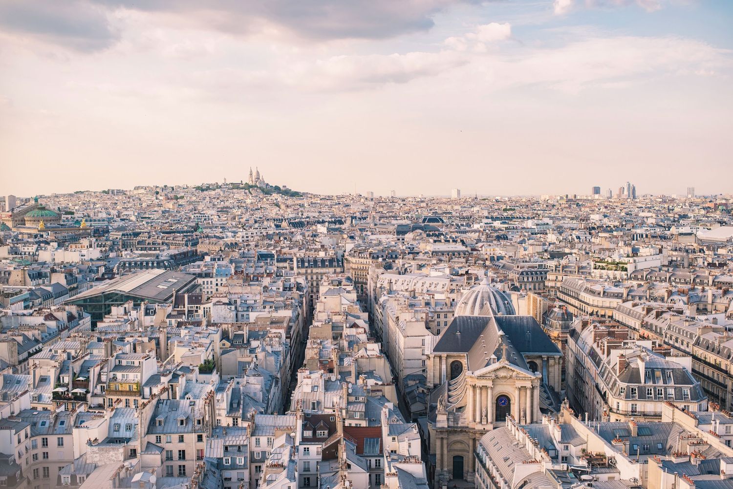 Aerial panorama of Paris cityscape showing dense urban architecture and iconic landmarks.