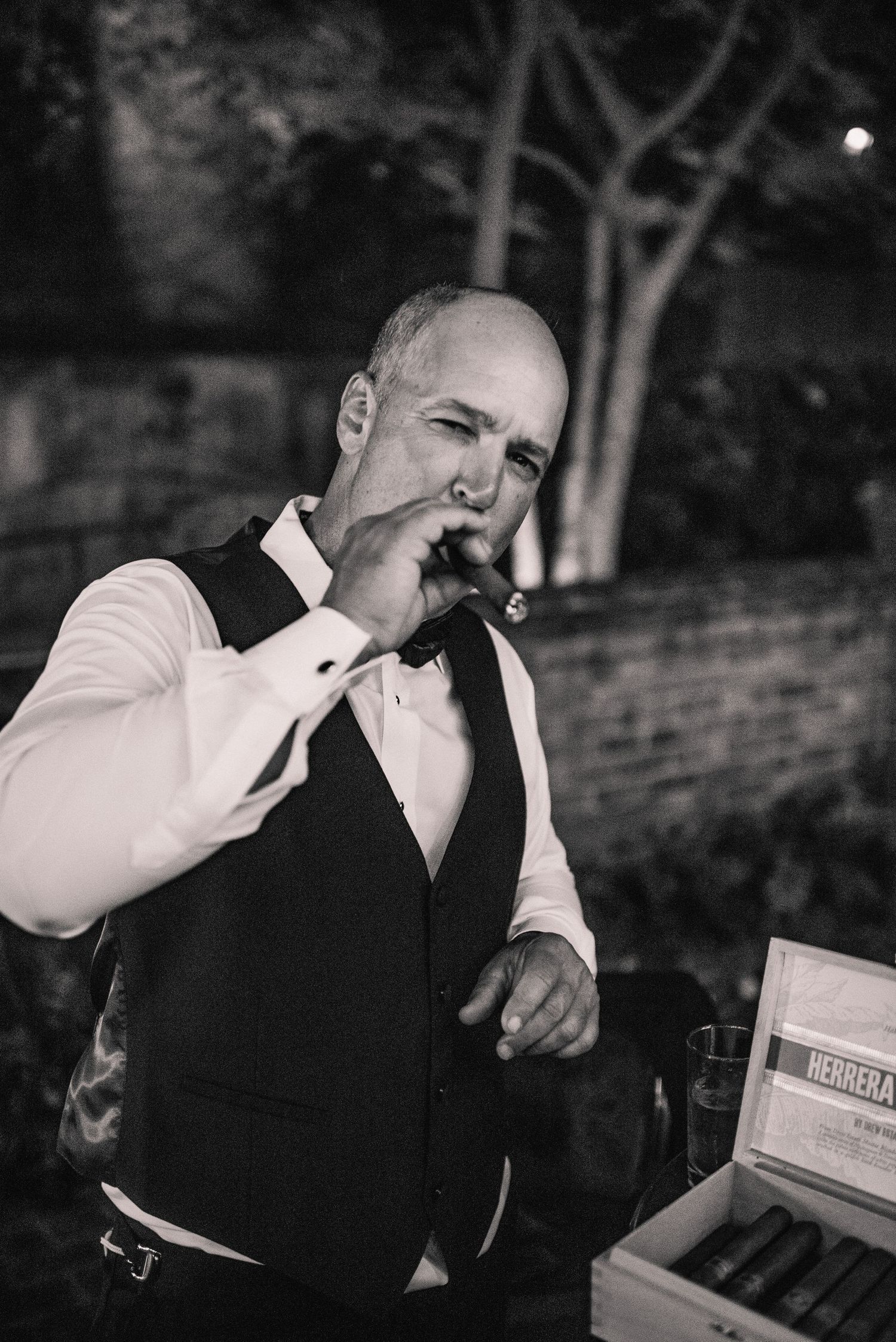 A sequence of black and white photos showing someone in formal attire smoking a cigar at an event.