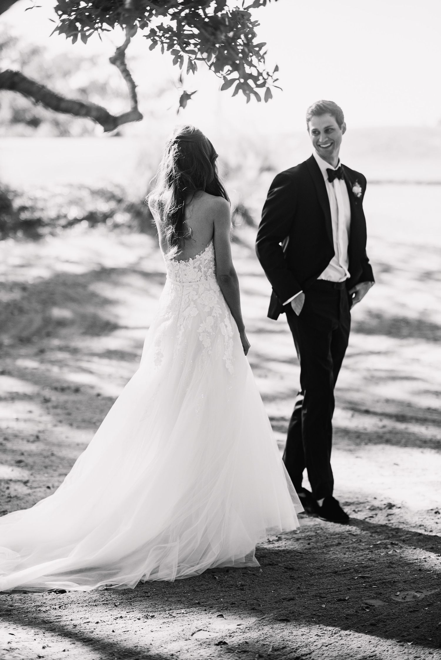 Black and white wedding photos showing a couple walking along a scenic beach path in formal attire.