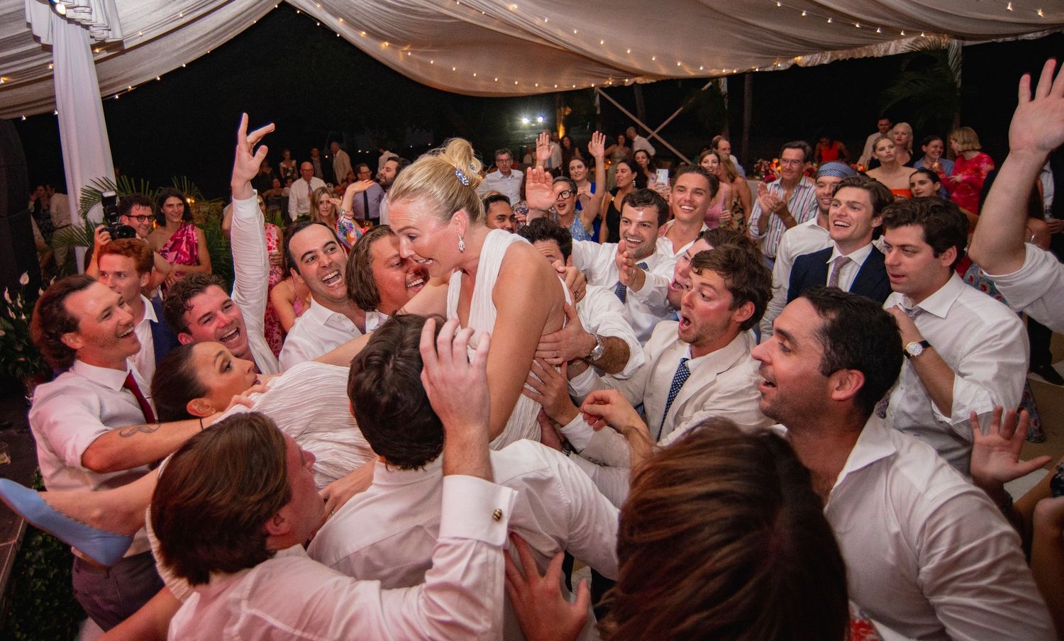 Wedding reception dance floor filled with celebrating guests in formal attire.