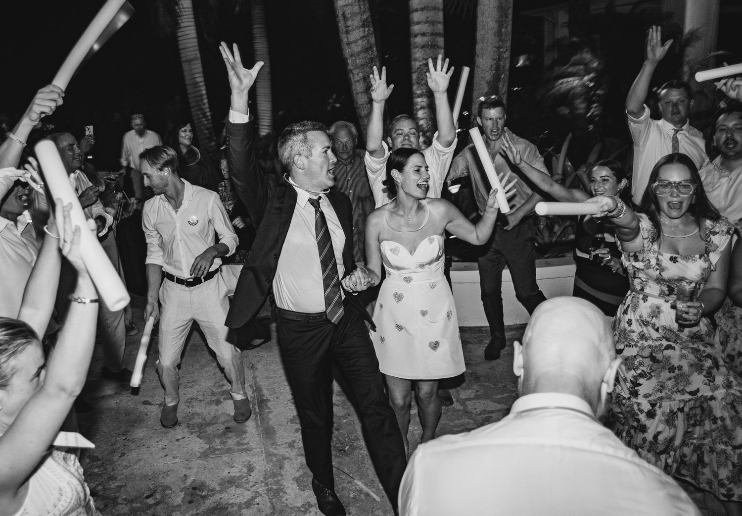 Wedding guests dance and celebrate together on a crowded dance floor at a reception party.