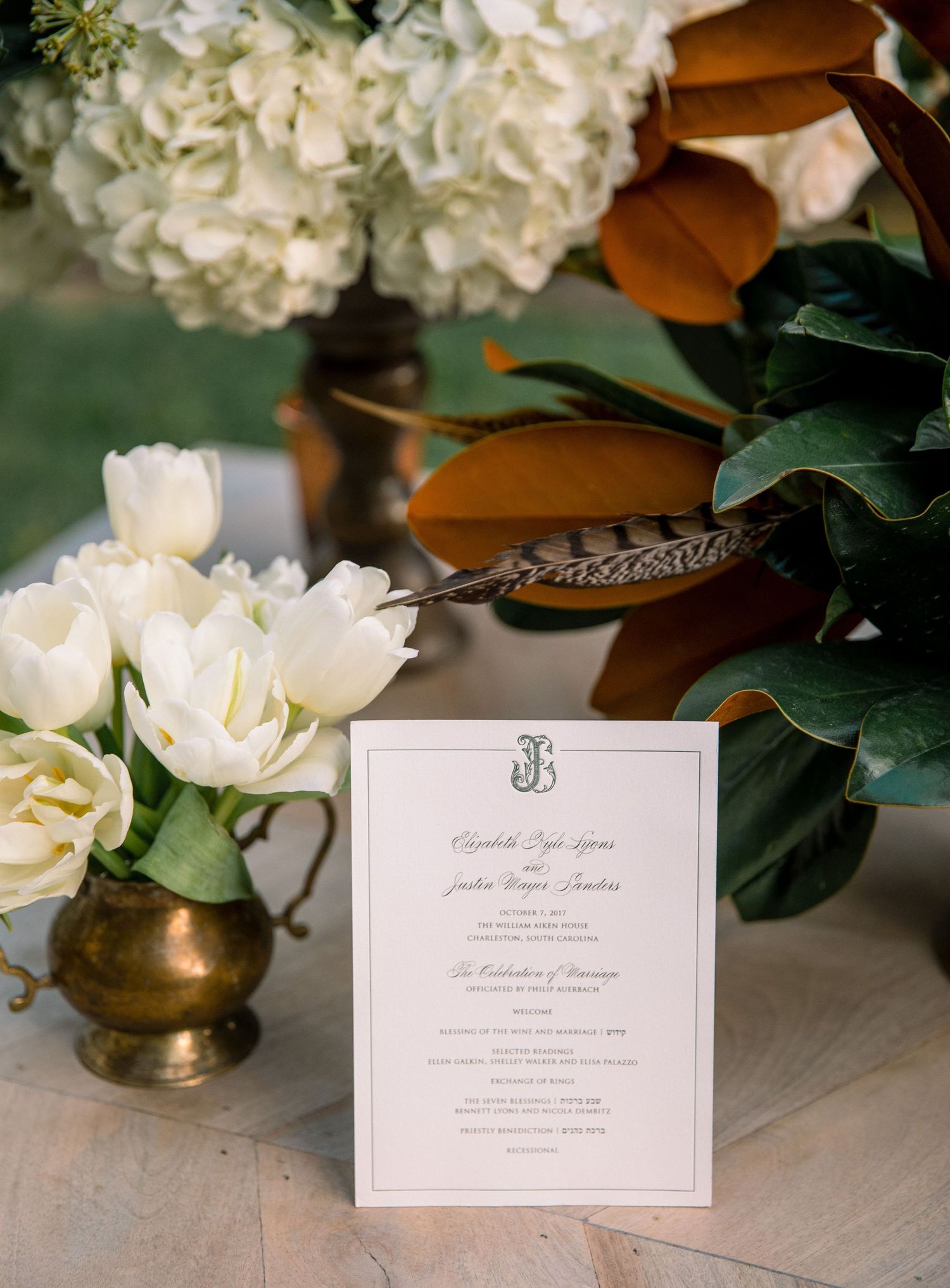 Elegant wedding stationery with monogram and floral arrangements displayed on a light gray surface with white hydrangeas.