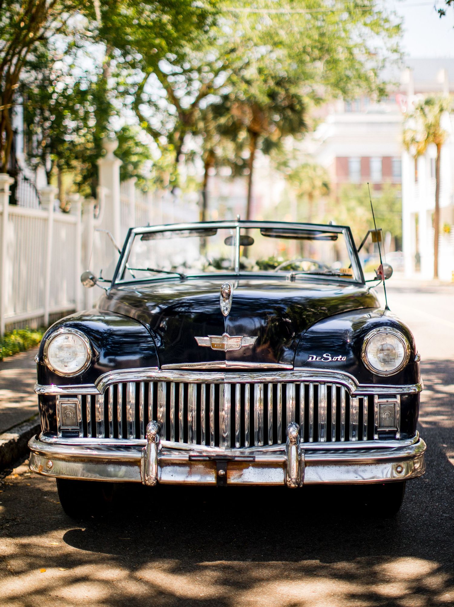 Classic black vintage car with chrome grille shown from multiple angles in a sunlit outdoor setting.