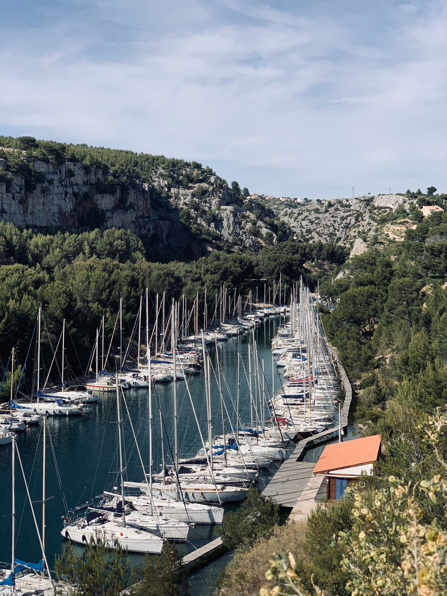 Marina filled with sailboats nestled between steep limestone cliffs in Calanques National Park, France.
