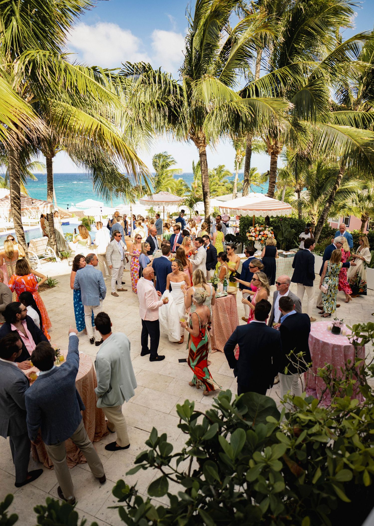 Large group of wedding guests gathered on a palm-lined beach for an outdoor celebration at Coral Sands in Harbour Island