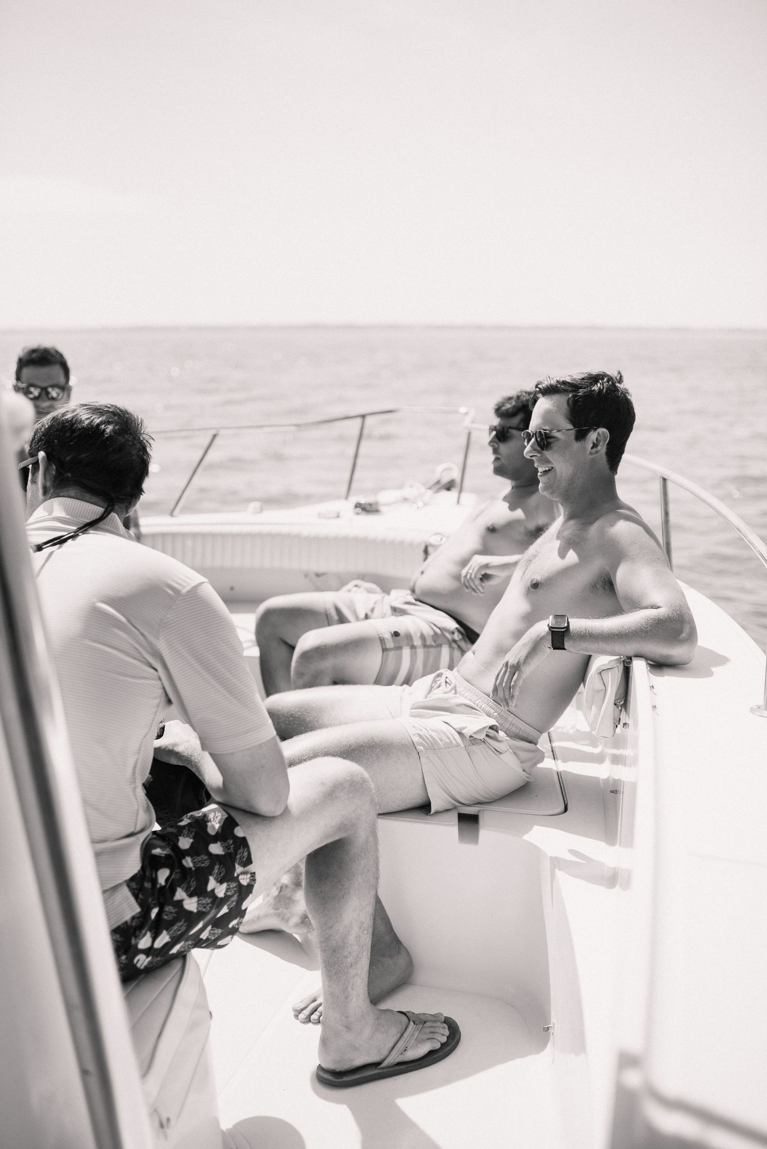 Black and white image of people relaxing on a boat deck during a summer day.